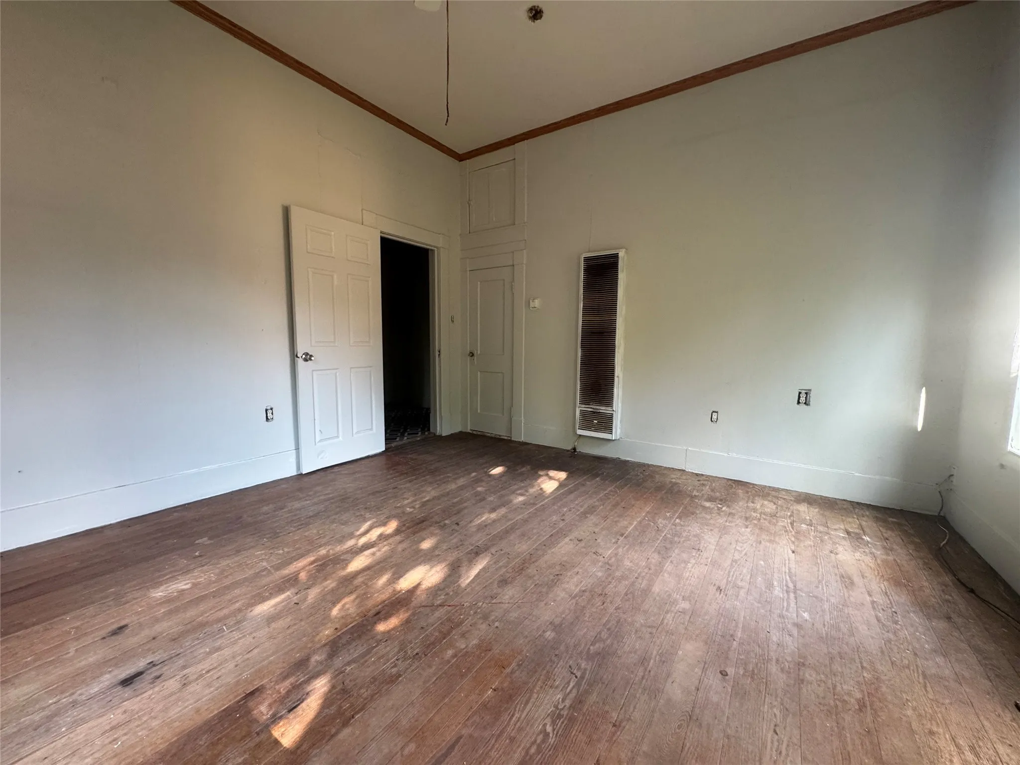 Hardwood flooring extending throughout the room, accented by white baseboards and neutral wall tones