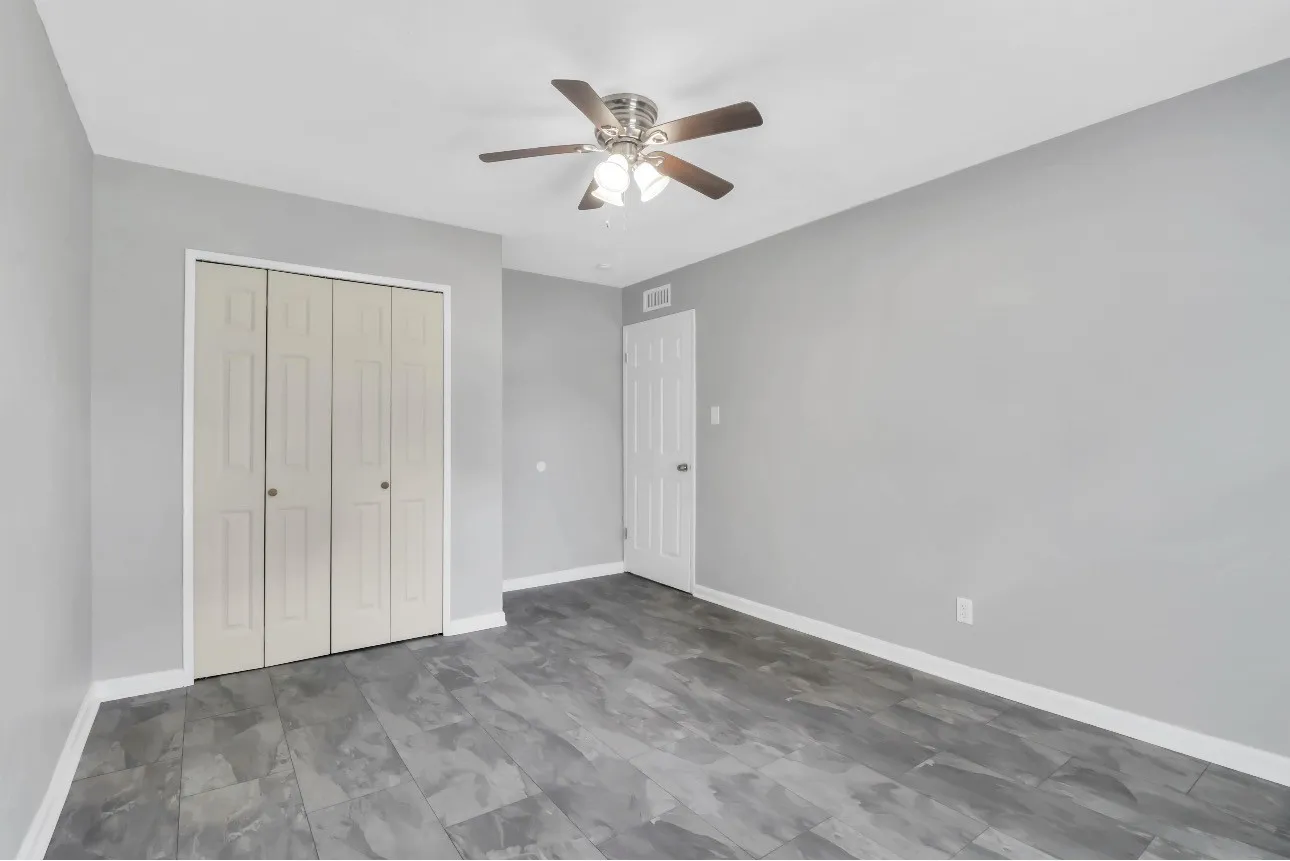 Spacious room featuring wood-finish flooring, a ceiling fan with integrated lighting, a bi-fold closet, and a white interior door