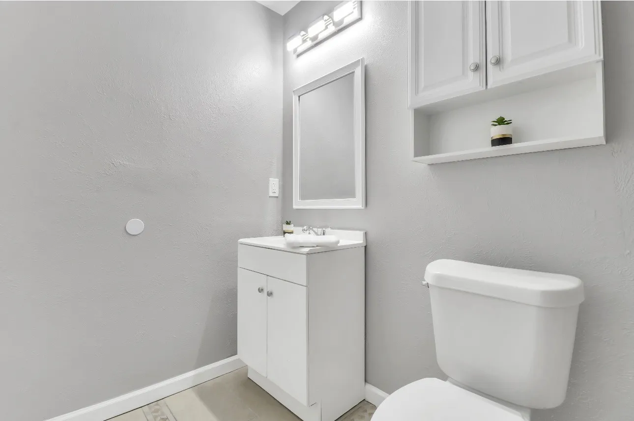 Bathroom featuring a white vanity with integrated sink, framed mirror, and chrome-finish light fixture