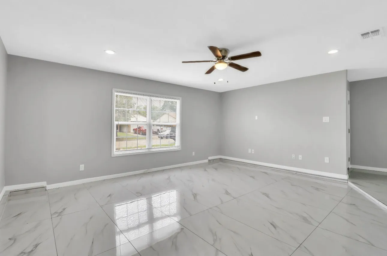 Spacious room featuring large format tile flooring, crisp white baseboards, and neutral gray walls