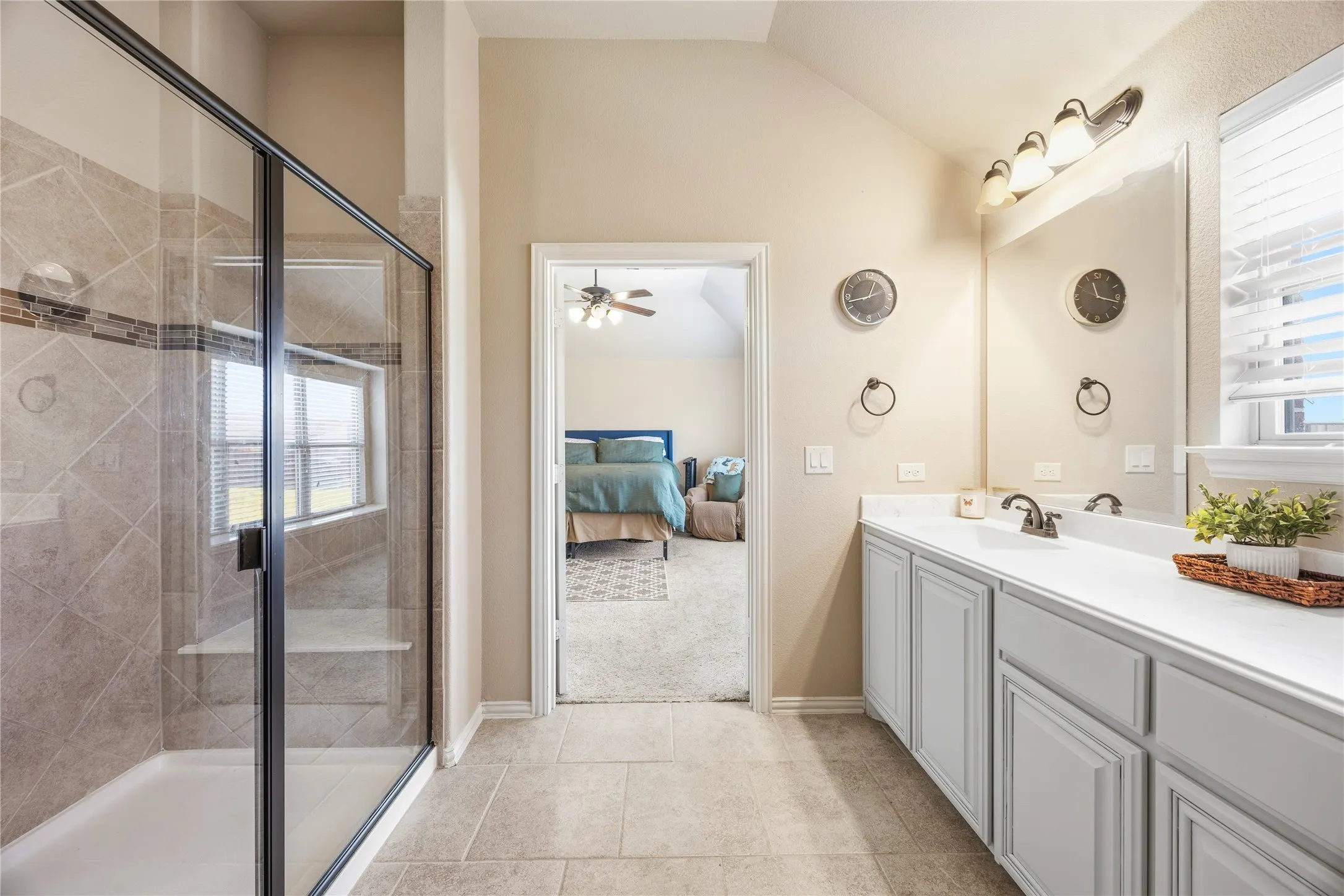 2nd floor primary bathroom two. Spacious bathroom featuring a glass-enclosed shower with tile surround and built-in bench, vanity with undermount sinks, and a large mirror