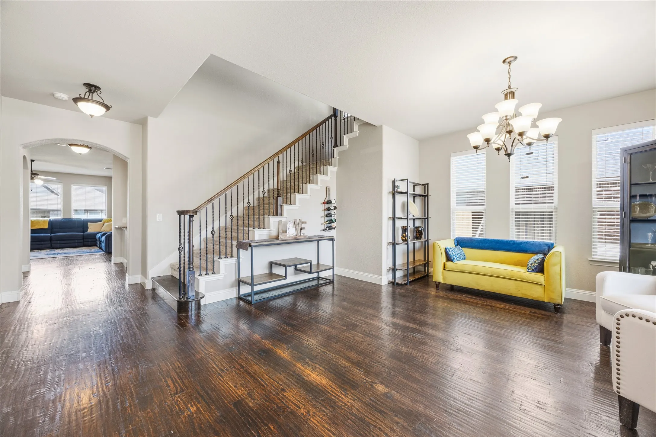 Open the front door to a spacious common area featuring wood-finish flooring, ample natural light from multiple windows, a prominent arched window. This is a sight to see.