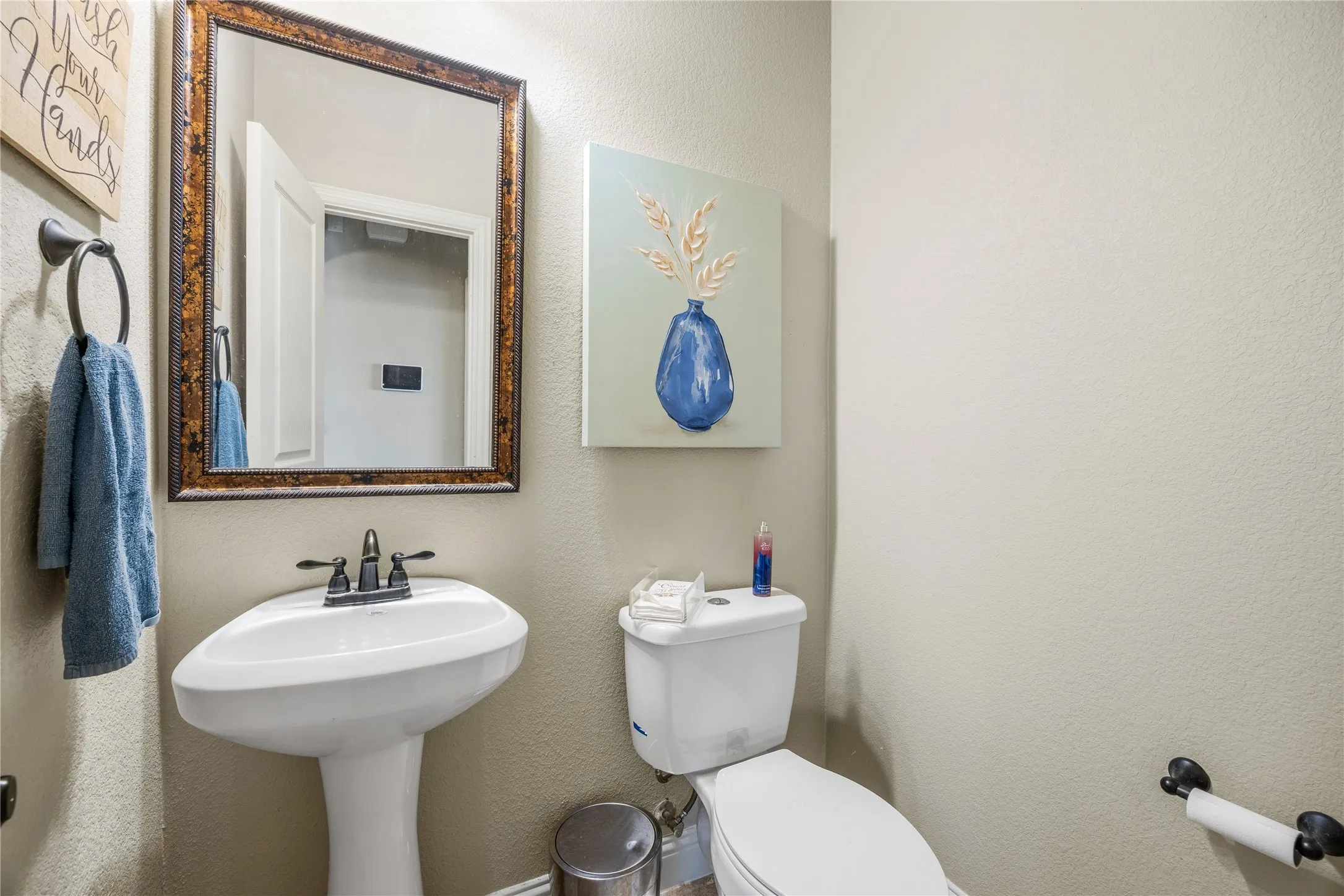 Half-bath 1 floor. Pedestal sink with oil-rubbed bronze faucet, framed mirror, and coordinating towel ring