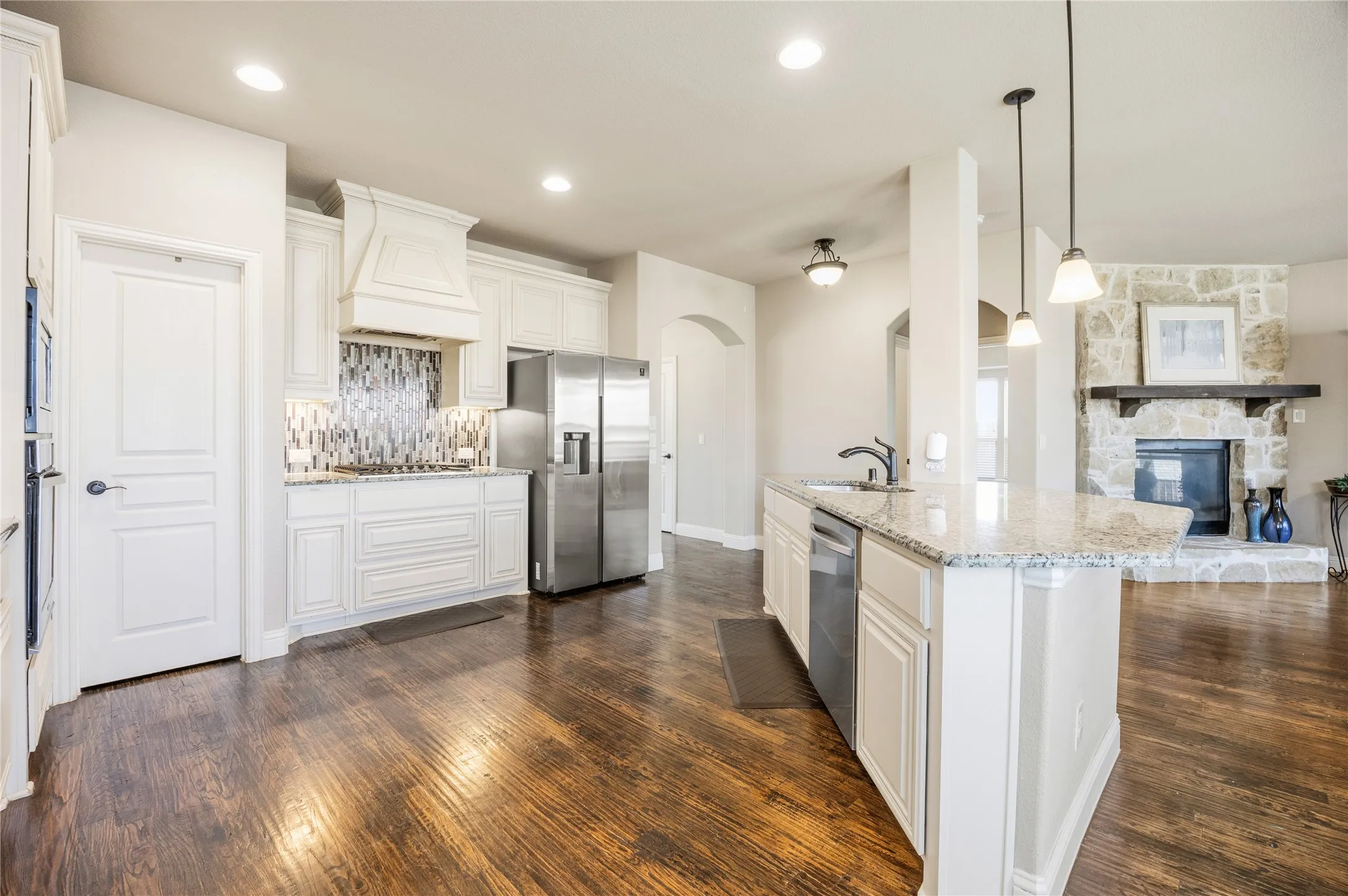 Open-concept kitchen featuring white cabinetry, granite countertops, and wood-finish flooring