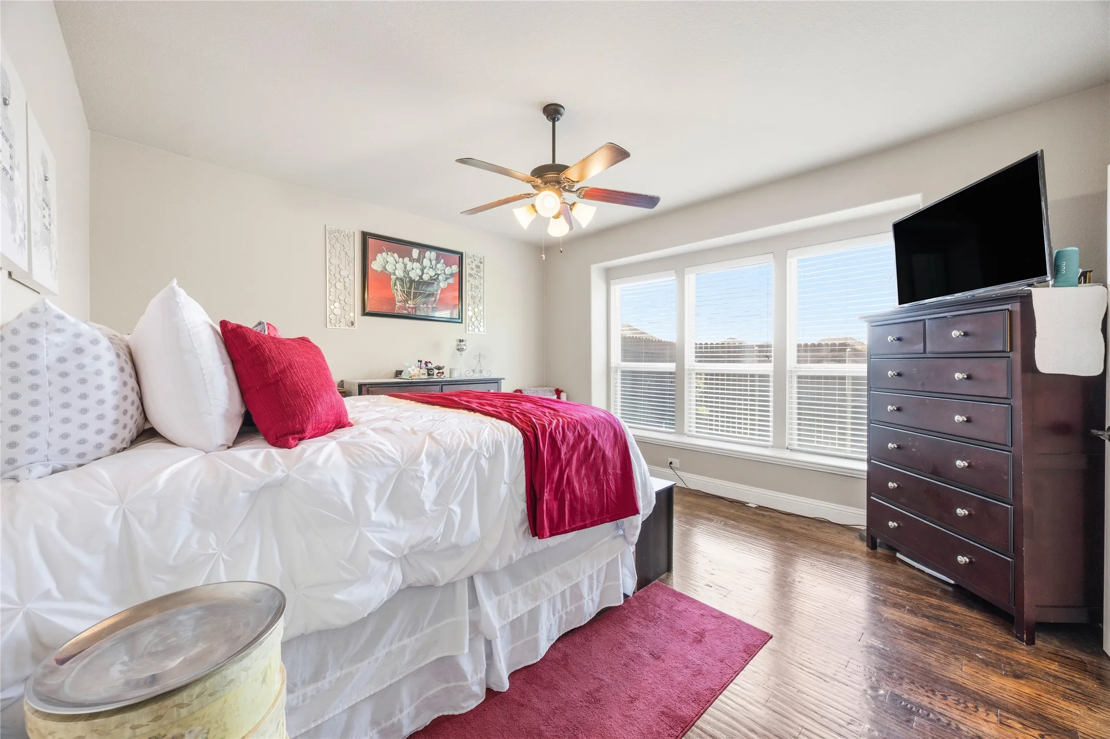 1st floor Primary Bedroom one featuring a multi-pane window, wood-finish flooring, and a ceiling fan with integrated lighting