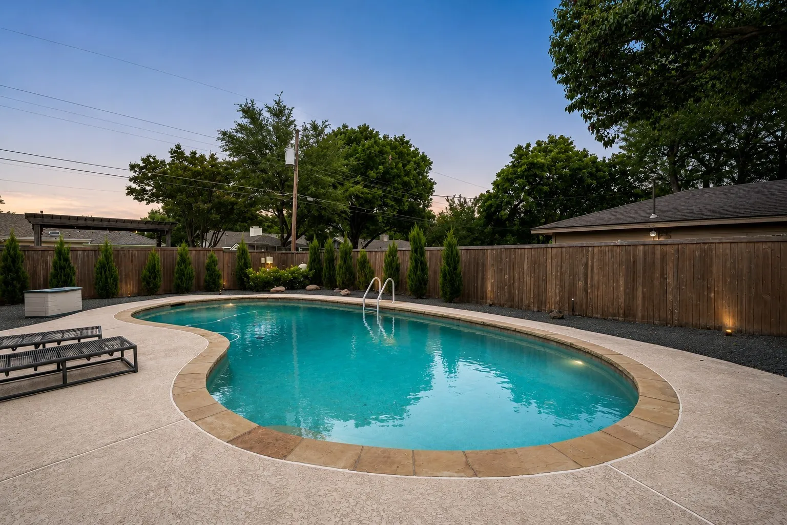 Freeform swimming pool featuring a textured concrete surround and natural stone coping