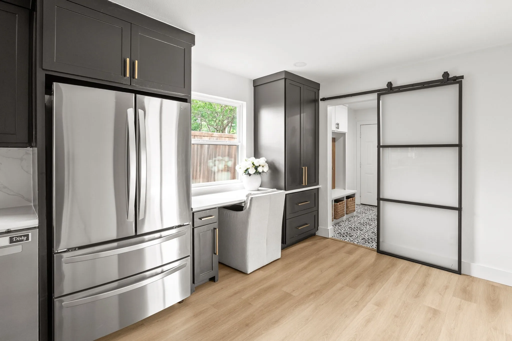 Sleek stainless steel refrigerator integrated into dark cabinetry with brass hardware