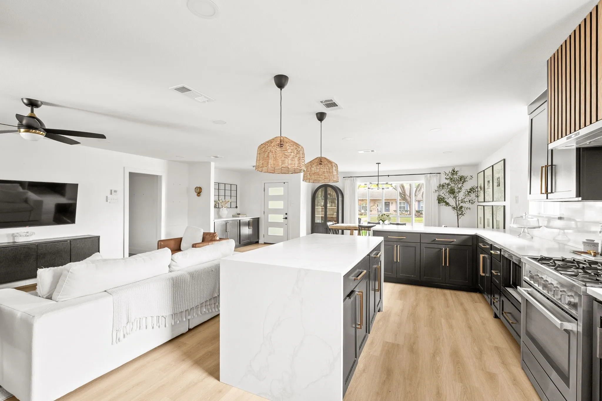 Open-concept living space featuring a gourmet kitchen with a central island, dark cabinetry, and light countertops