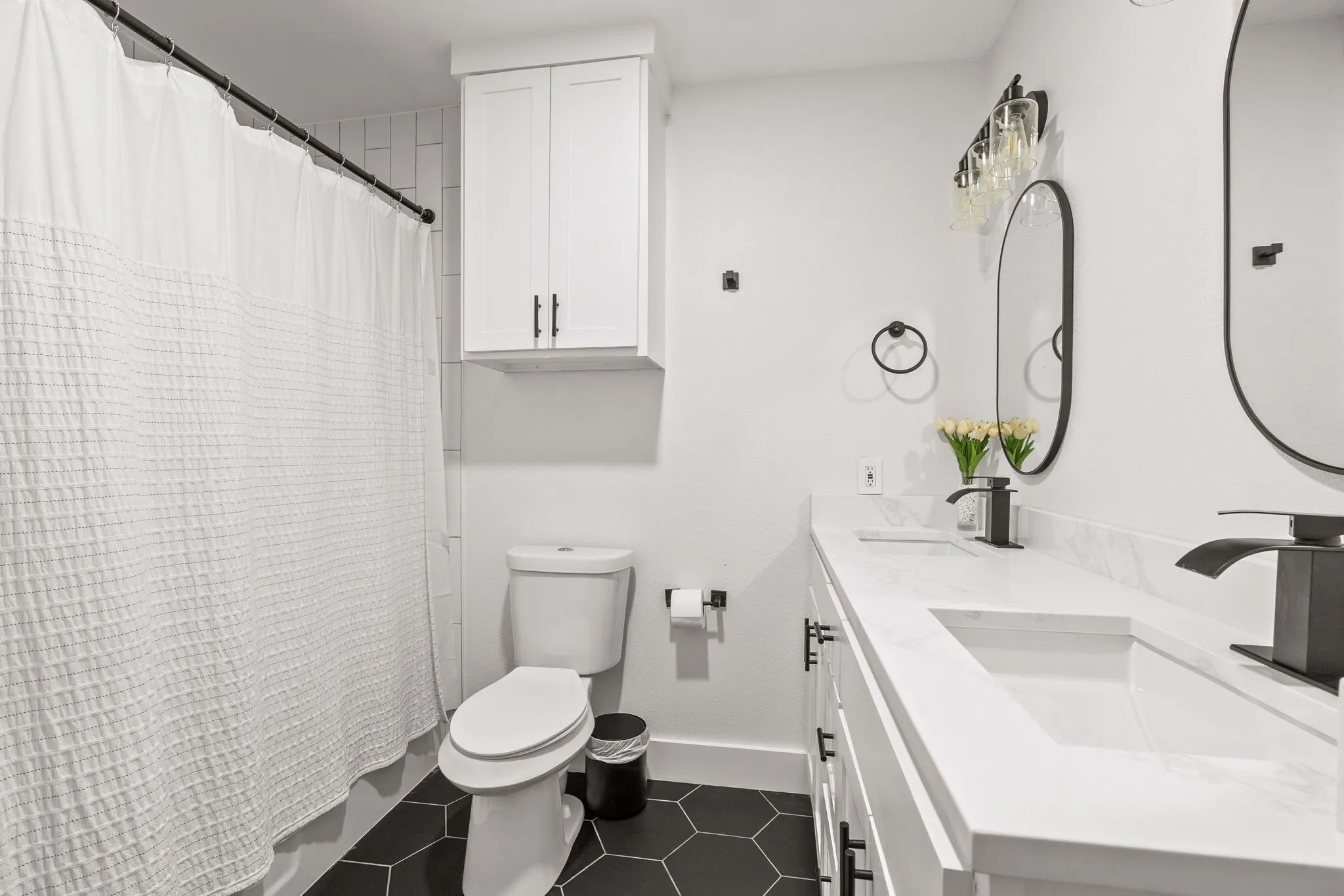 Bathroom featuring a dual vanity with undermount sinks, white countertops, and matte black fixtures