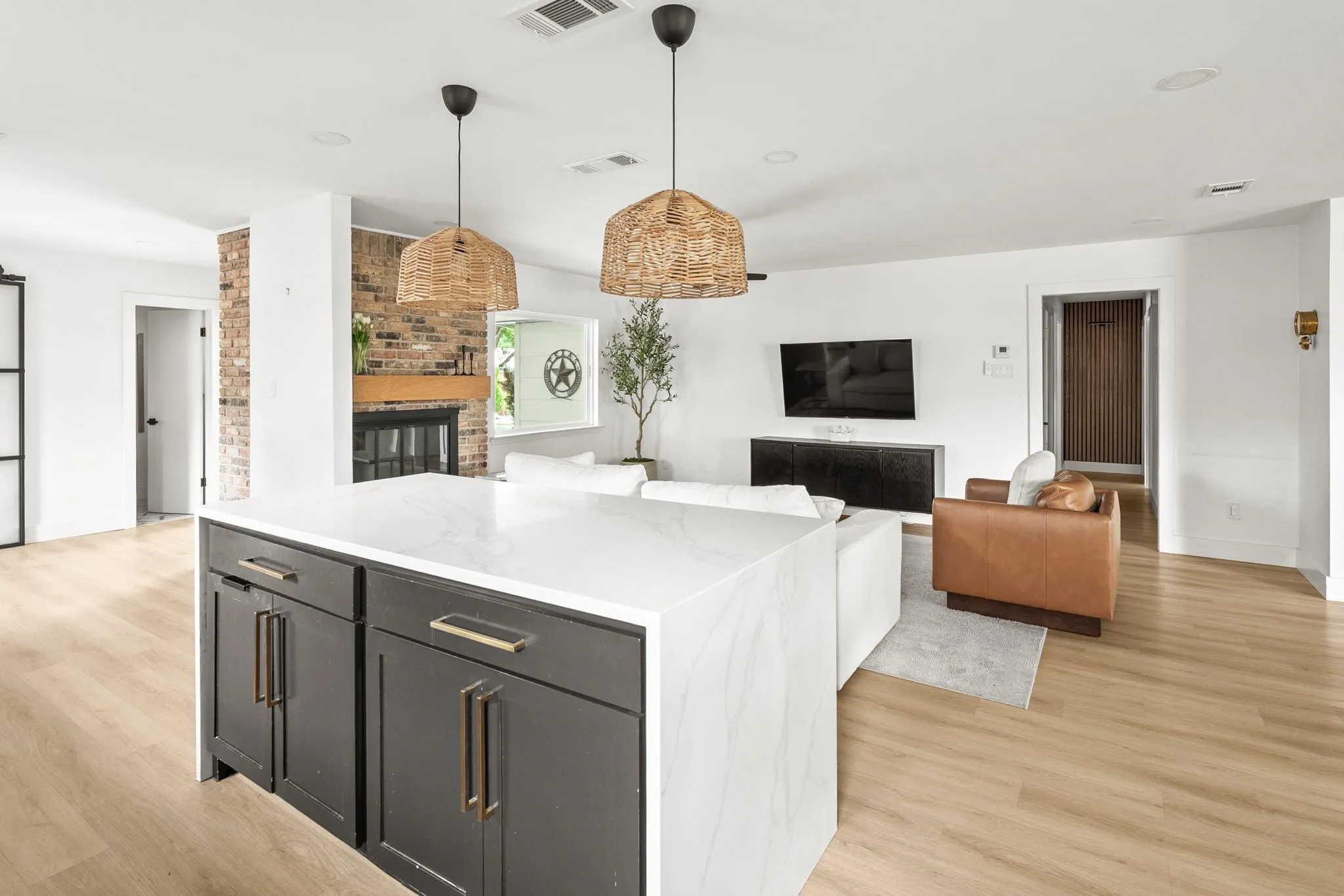 Kitchen island with a waterfall countertop, dark cabinetry, and bronze hardware
