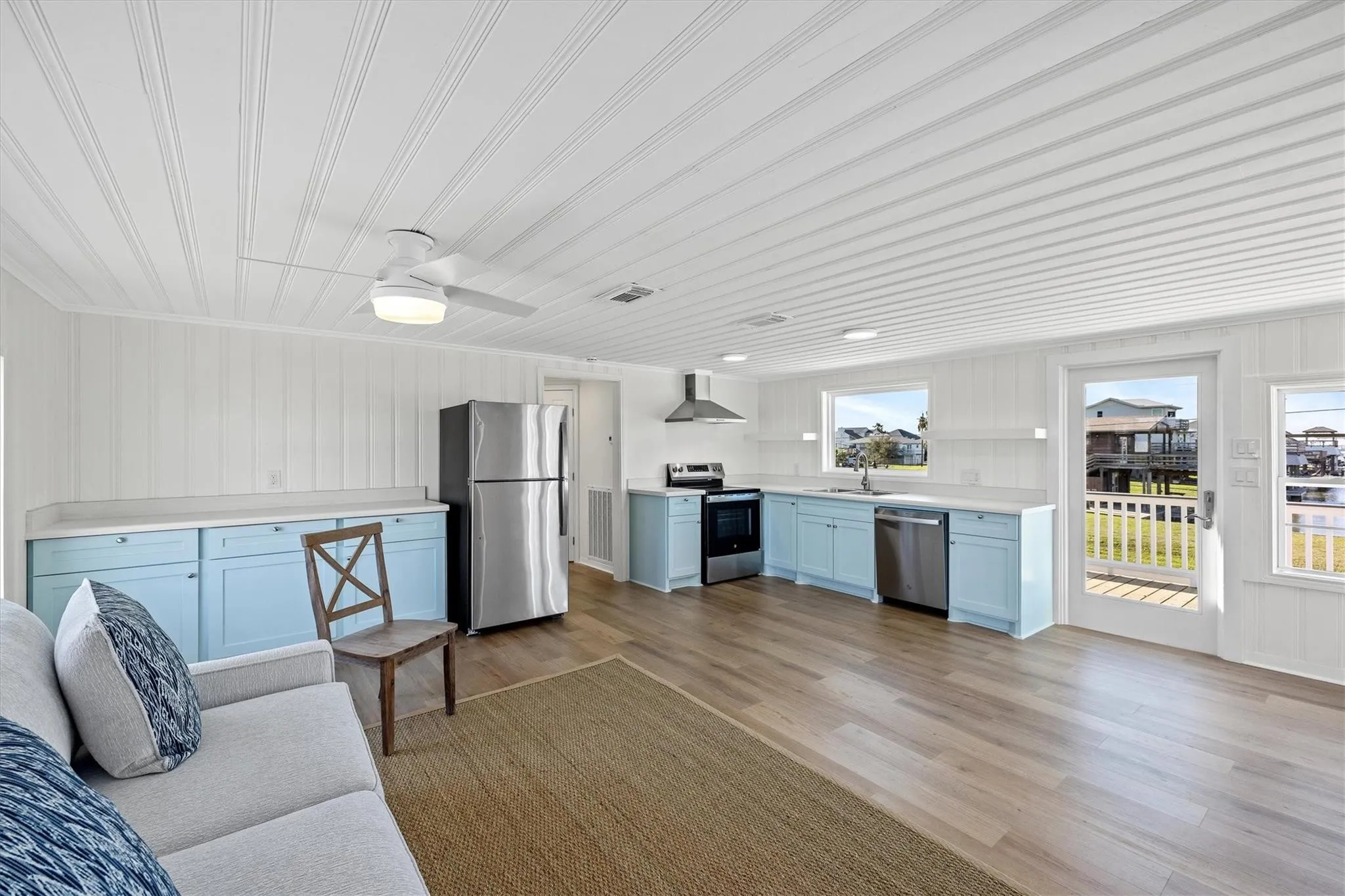 Open-concept living space featuring wood-finish flooring, white beadboard walls, and a matching beadboard ceiling with recessed lighting and a ceiling fan
