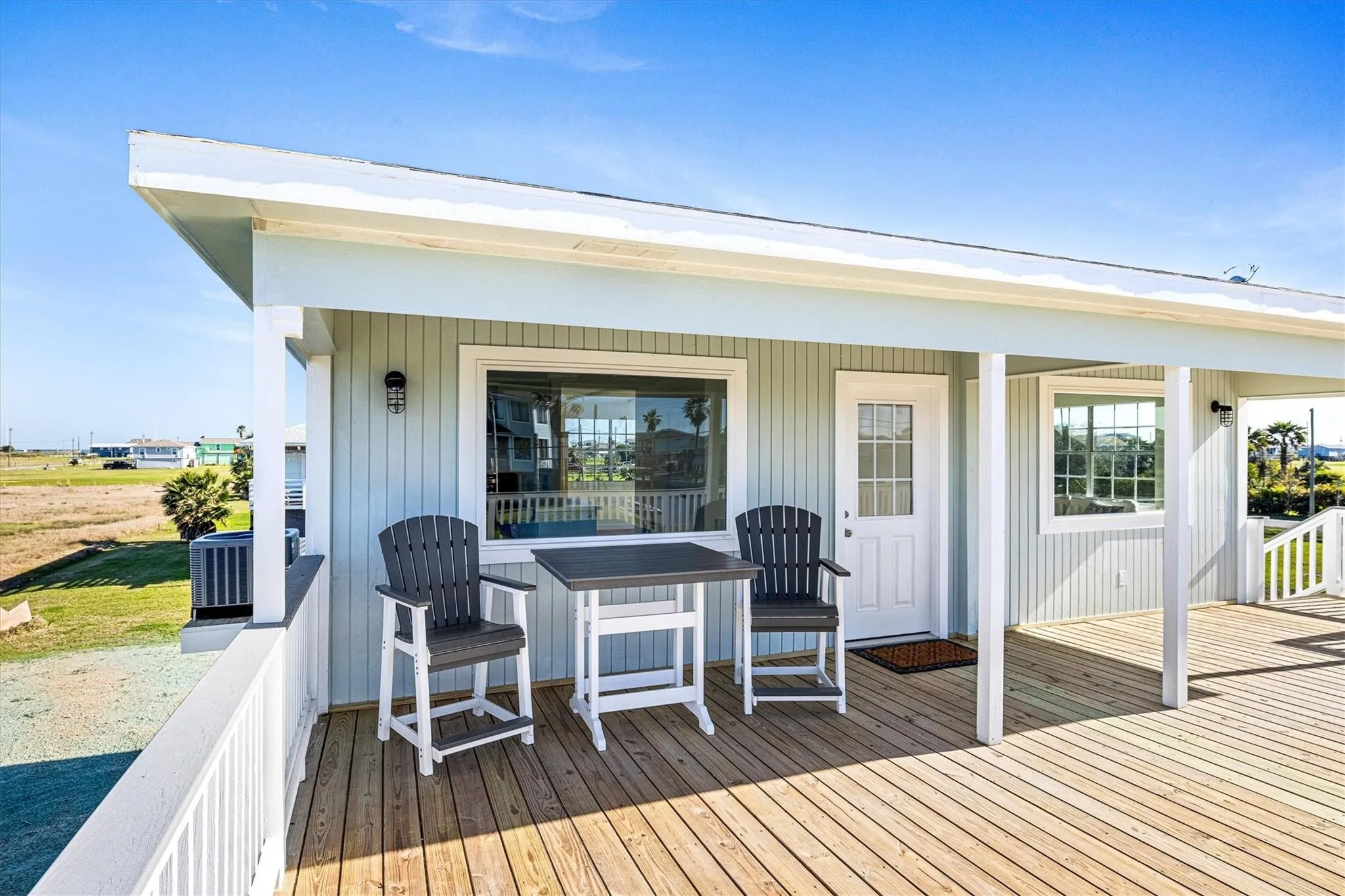 Spacious wood-finish deck with white railings and blue exterior siding