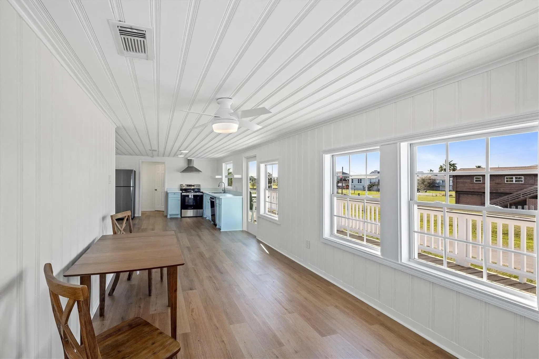 Open-concept living area featuring wood-finish flooring, white shiplap walls, and a matching paneled ceiling