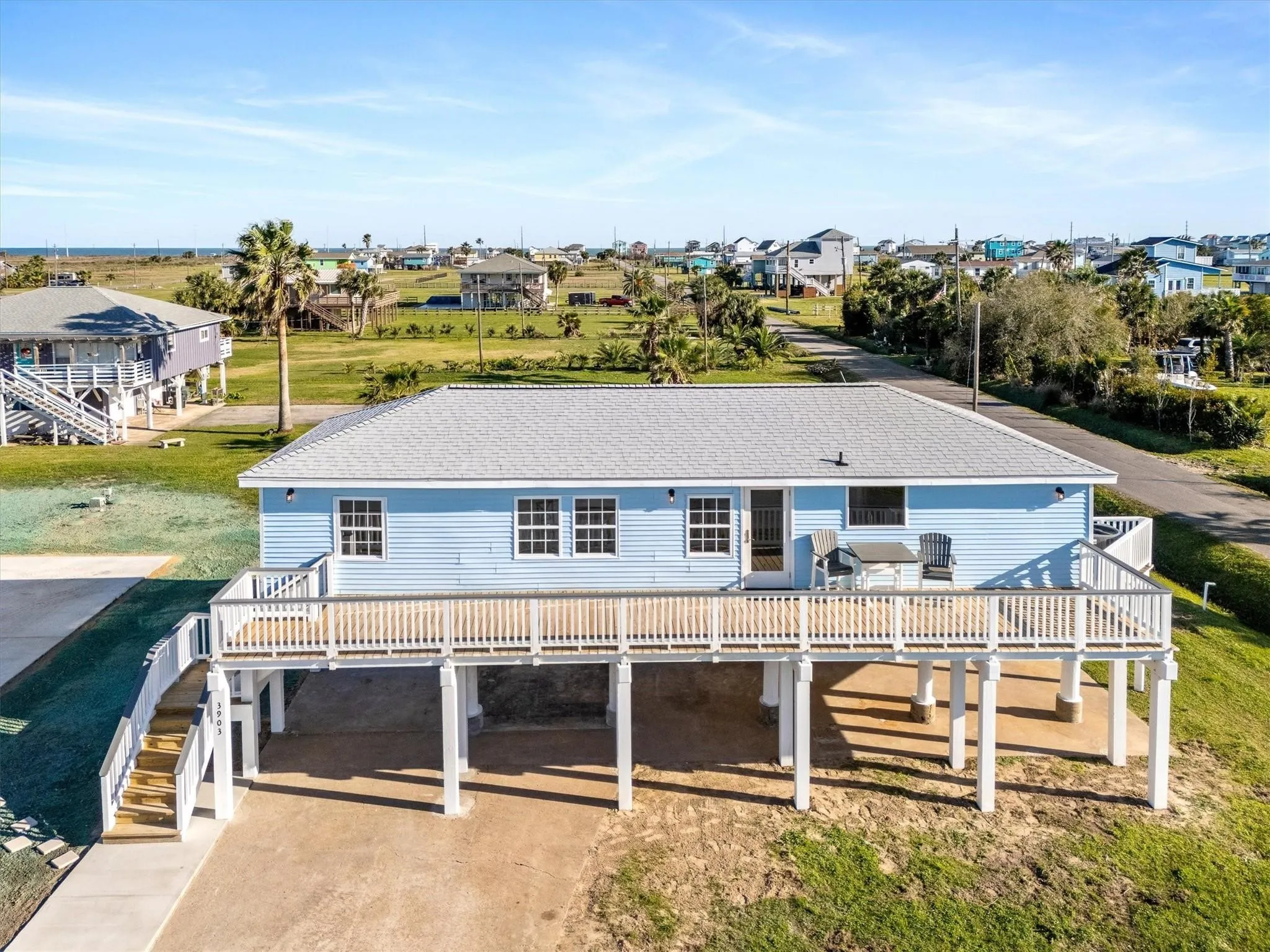 Elevated coastal residence featuring light blue siding and a light gray roof