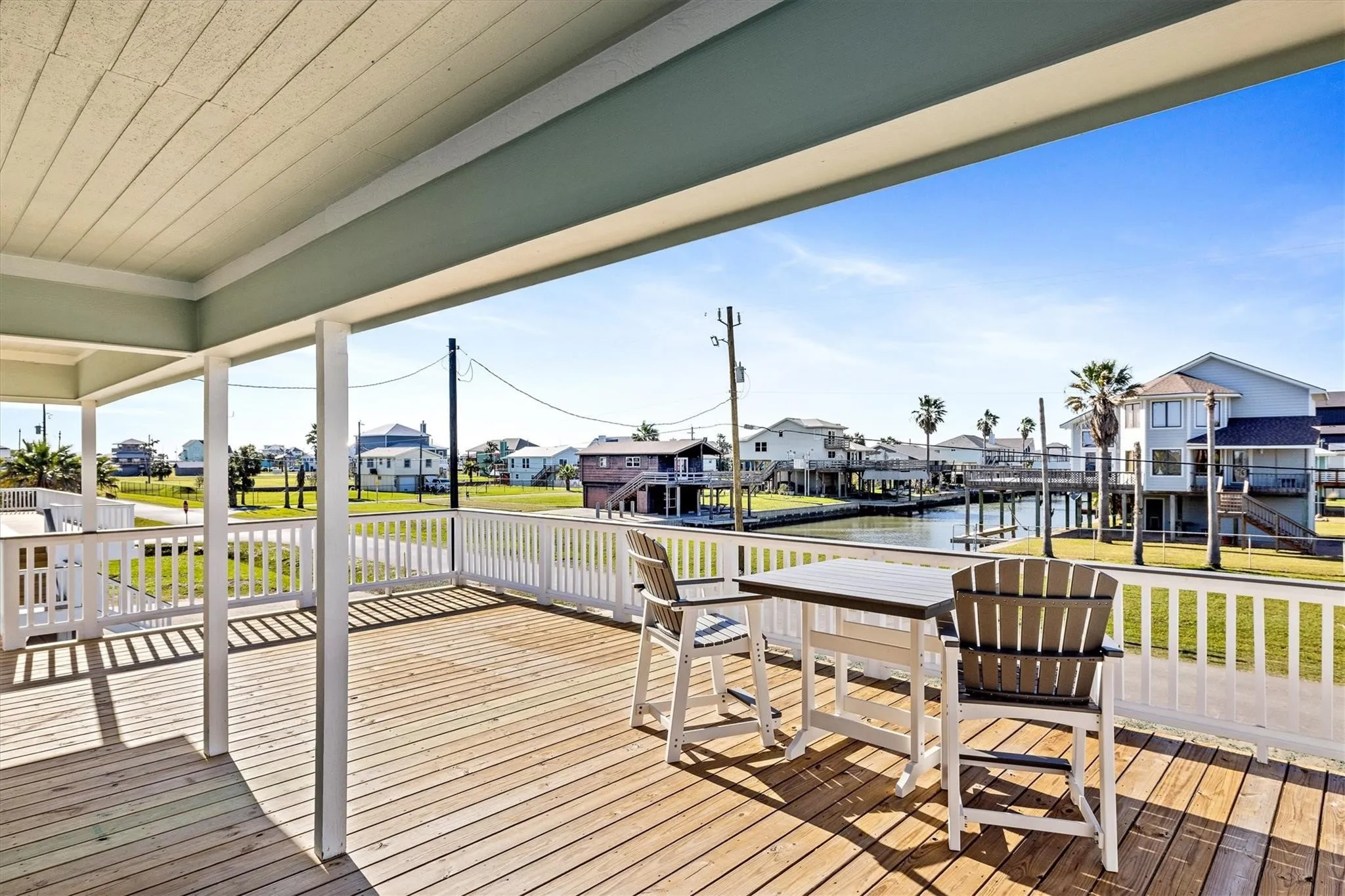 Expansive covered deck featuring natural wood decking, white railing, and a light blue ceiling