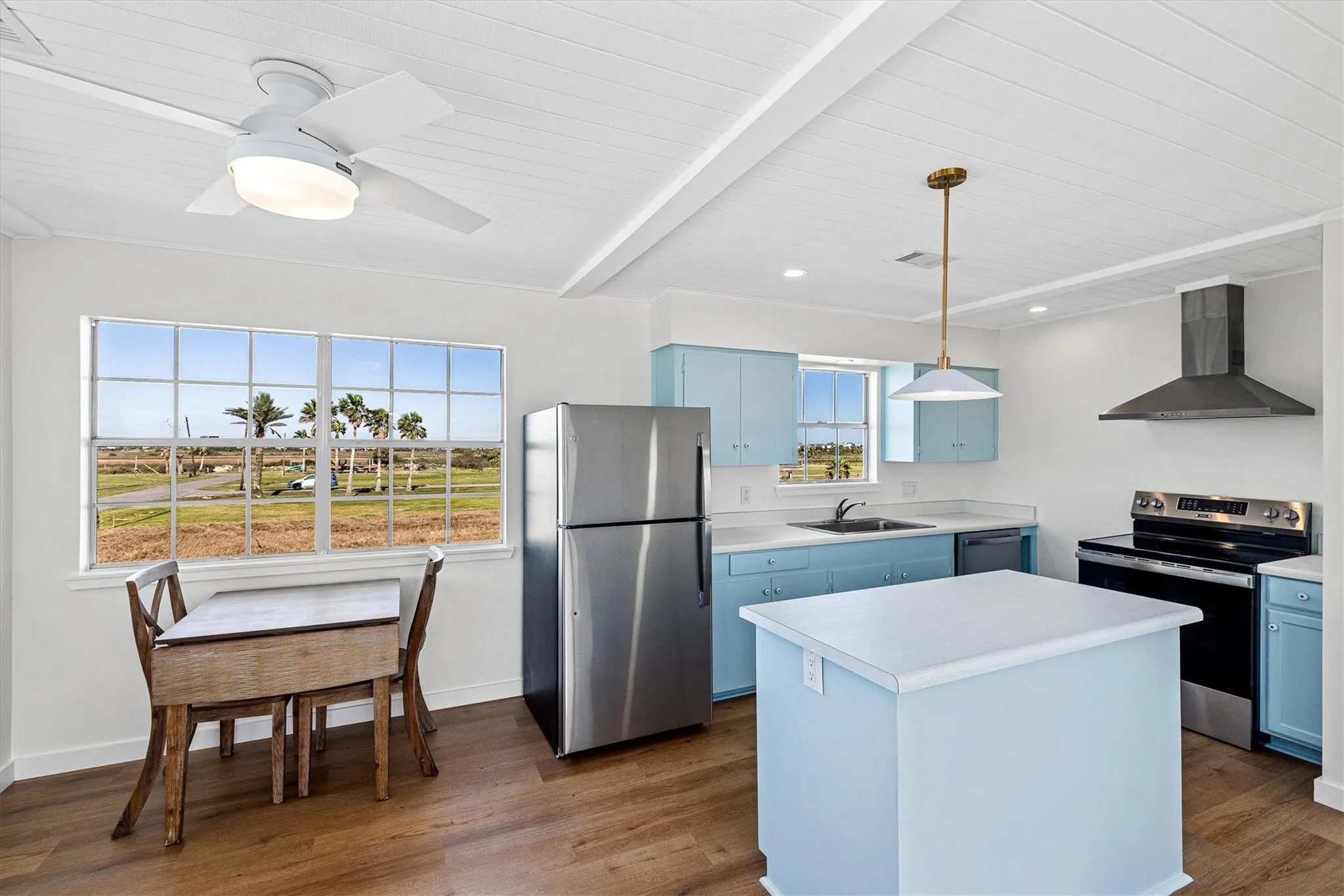 Kitchen featuring light blue cabinetry, white countertops, wood-finish flooring, and stainless steel appliances