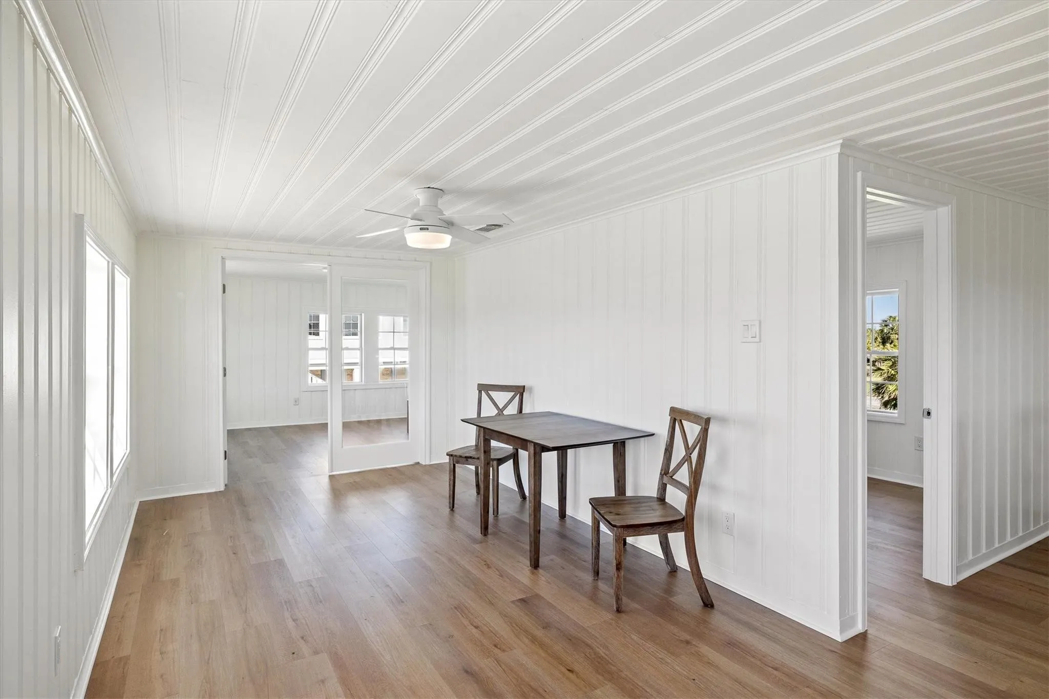 Interior room featuring wood-finish flooring, white vertical plank walls, and a white plank ceiling
