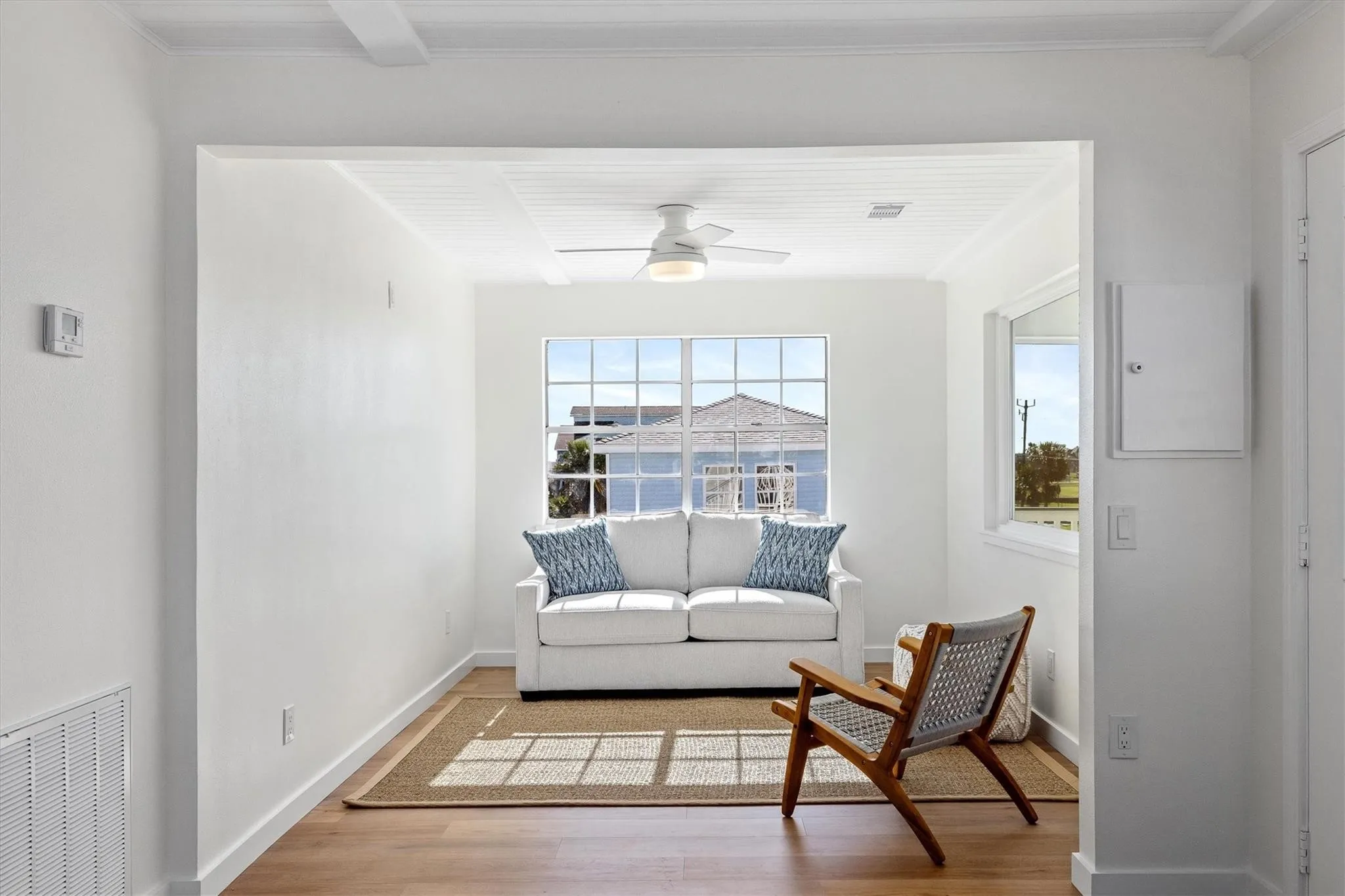 Naturally lit interior space featuring wood-finish flooring, white walls, and a window providing exterior views