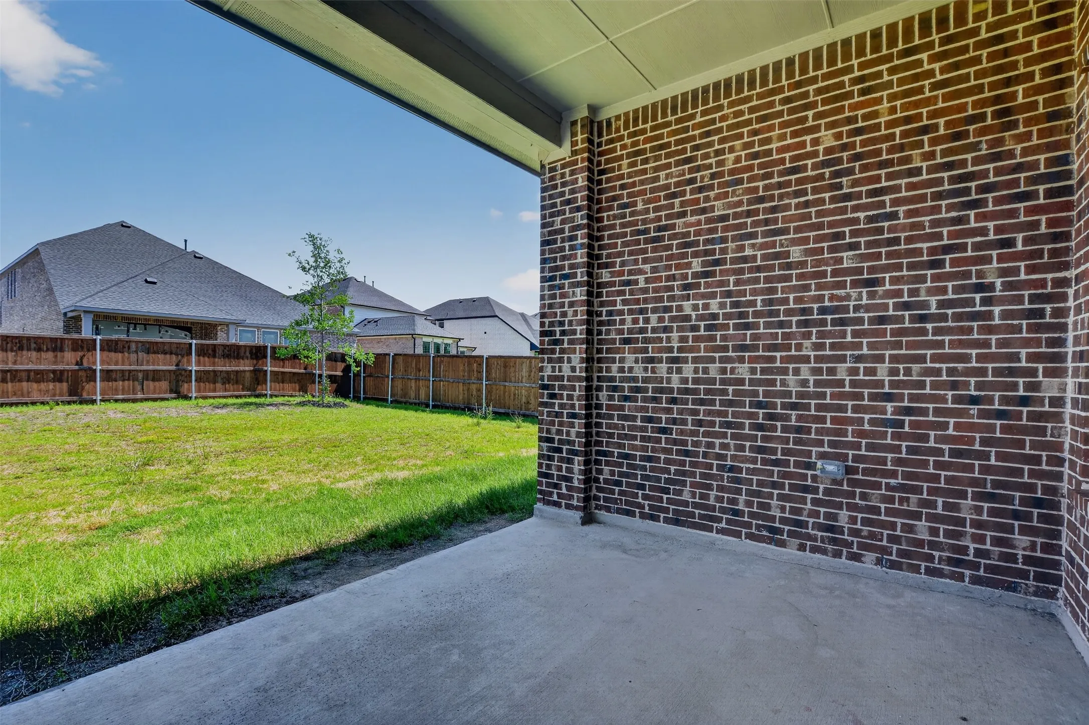 Covered patio featuring a concrete slab and a brick exterior wall