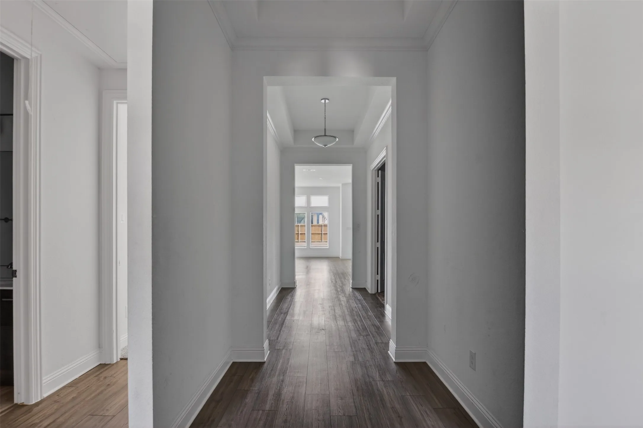Hallway featuring wood-finish flooring, recessed lighting, crown molding, and a tray ceiling detail