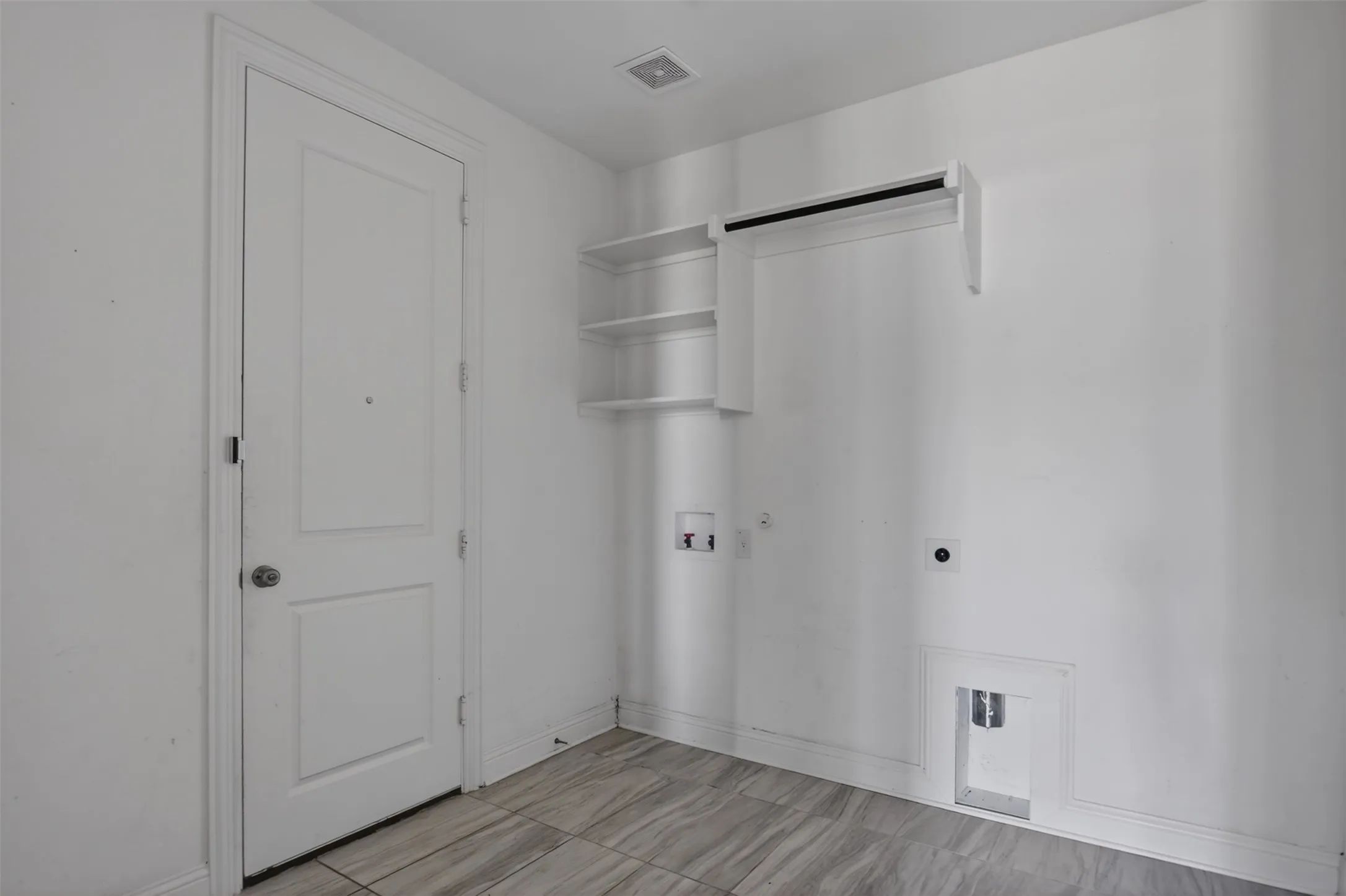 Laundry area featuring tile flooring, built-in shelving, and a hanging rod