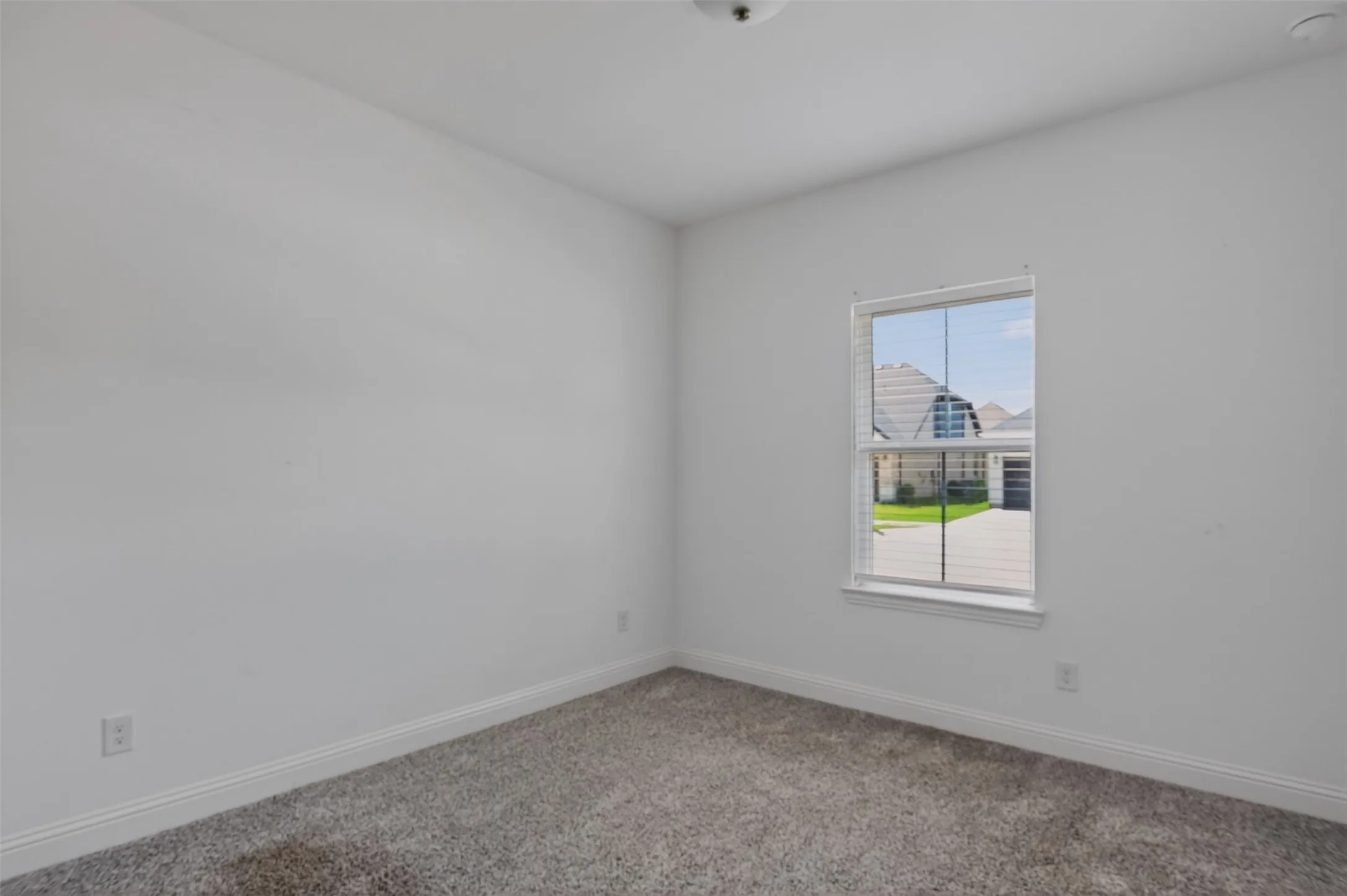 Room with neutral gray carpet flooring and white baseboards