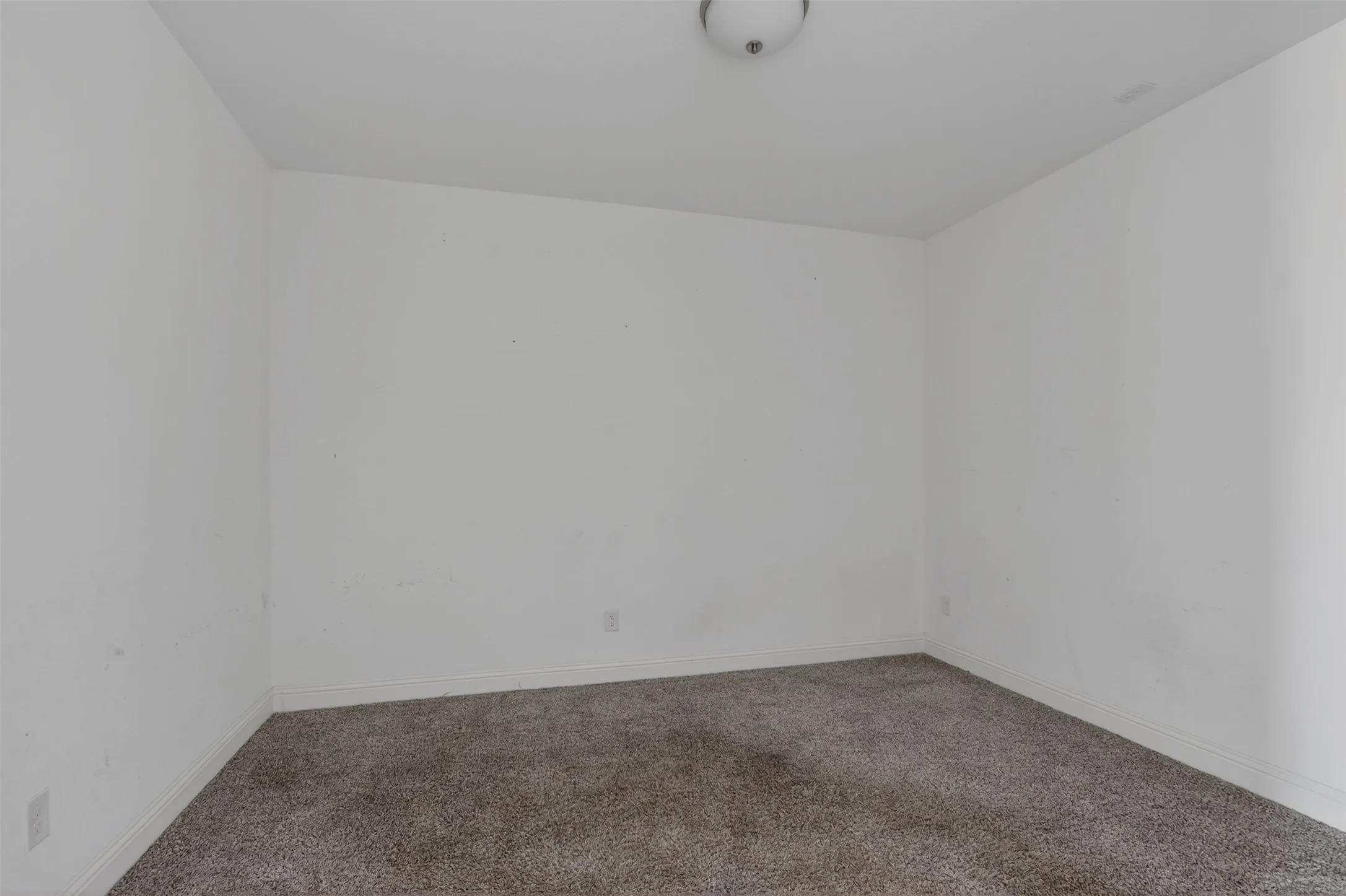 Interior room featuring light gray carpet, white baseboards, and a semi-flush ceiling light fixture