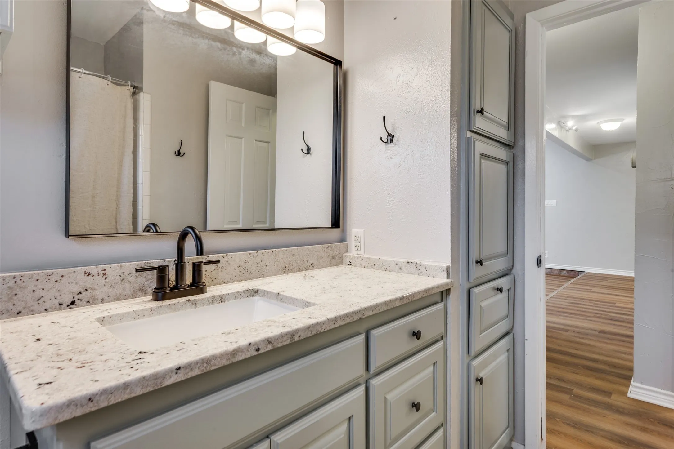 Bathroom vanity featuring a rectangular undermount sink, speckled countertop, and dark-finish faucet