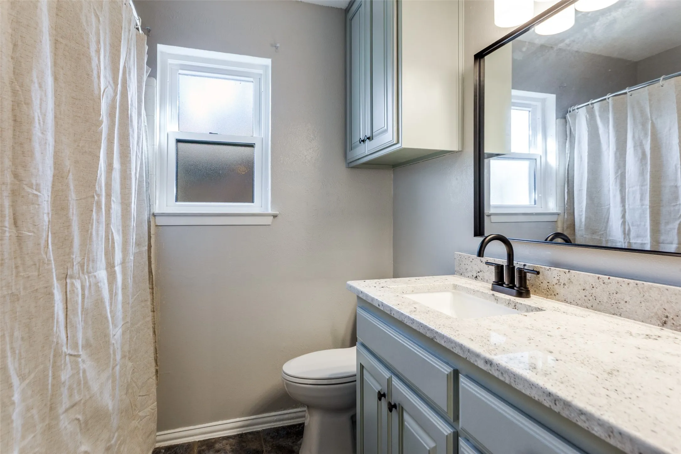 Bathroom with a light-toned vanity featuring a granite countertop and an integrated sink