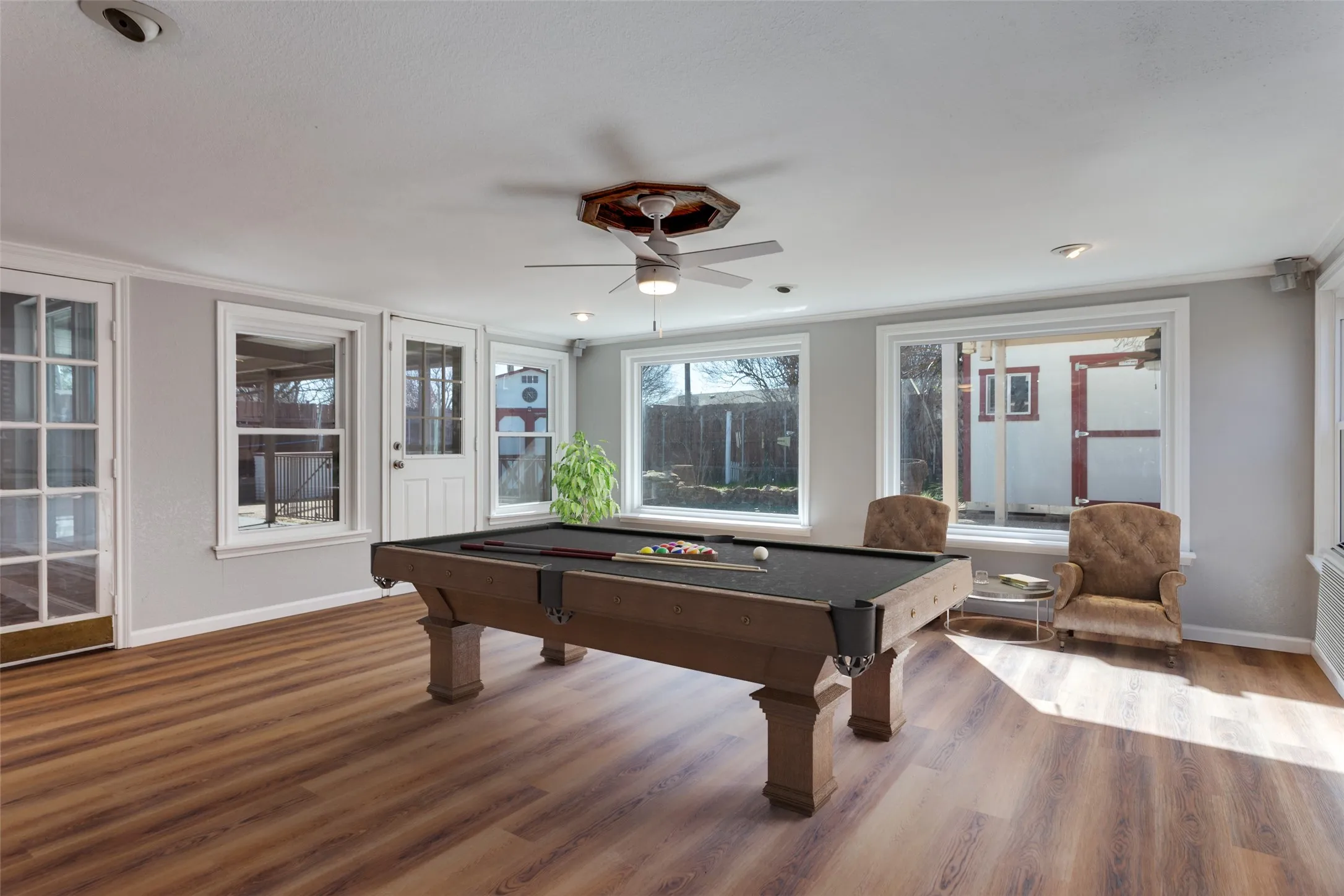 Spacious room featuring wood-finish flooring, multiple windows, a ceiling fan, and recessed lighting (virtual staging)