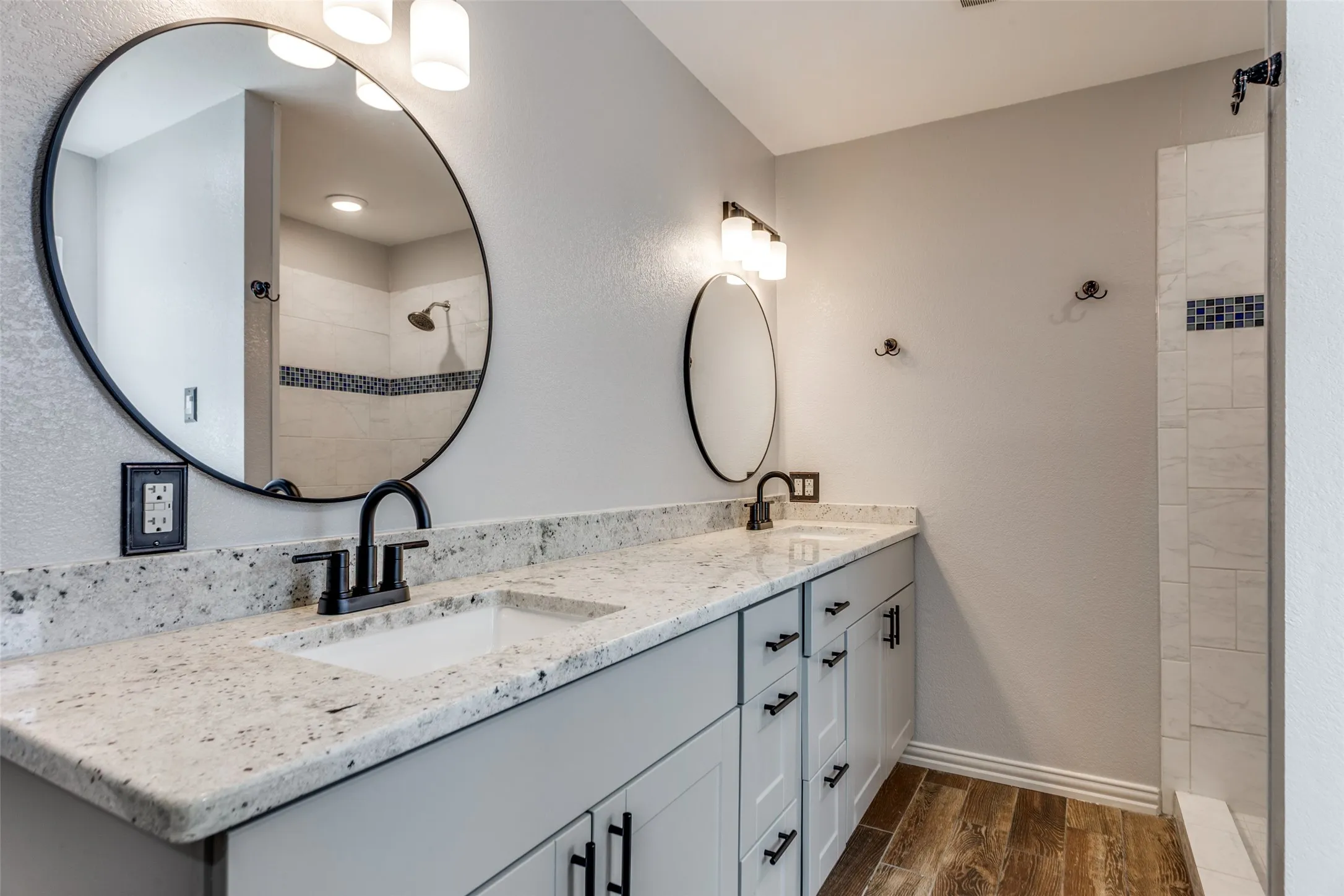 Dual vanity with light-colored countertops and undermount sinks, complemented by matte black fixtures