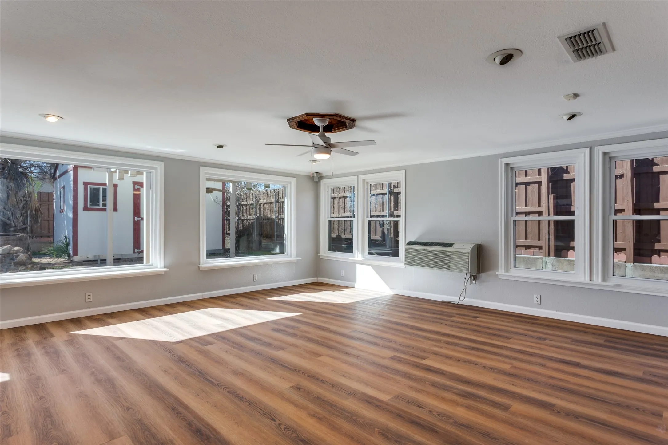 Spacious room featuring wood-finish flooring and multiple windows with white trim