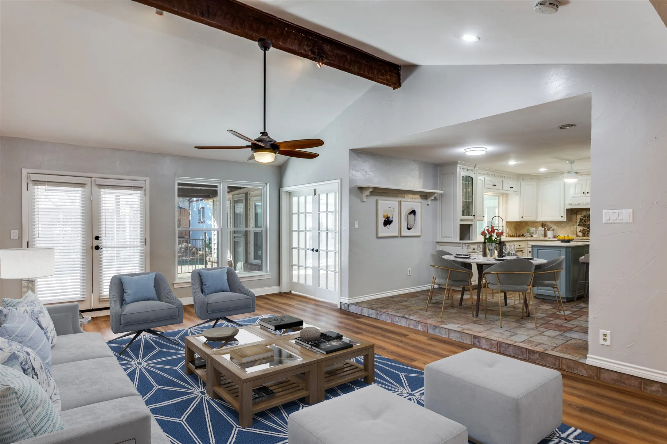 Vaulted ceiling living room featuring a wood beam and ceiling fan (virtual staging)