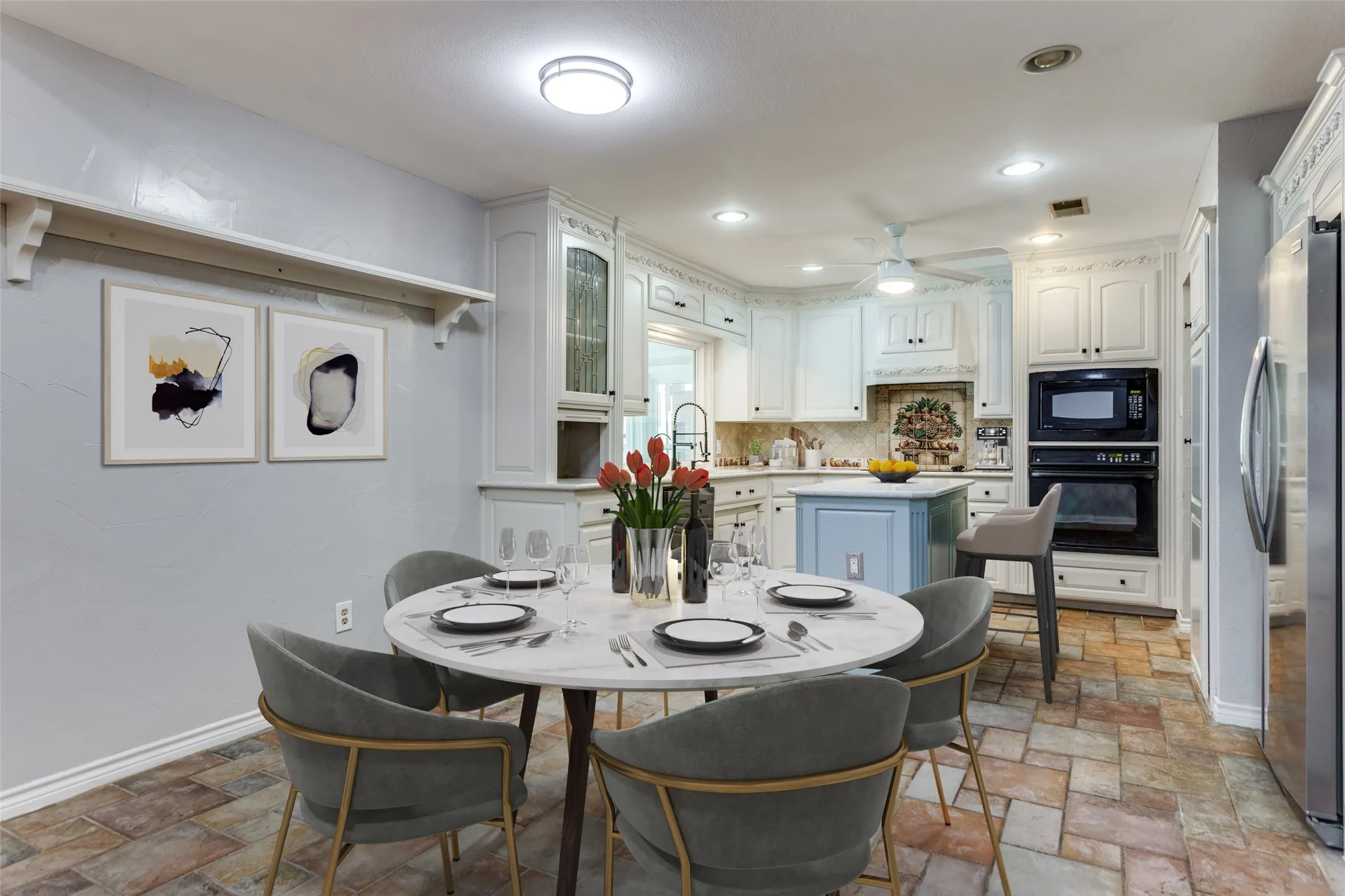 Kitchen featuring rustic tile flooring, white cabinetry with decorative molding, built-in double ovens, and a central island with a contrasting base (virtual staging)