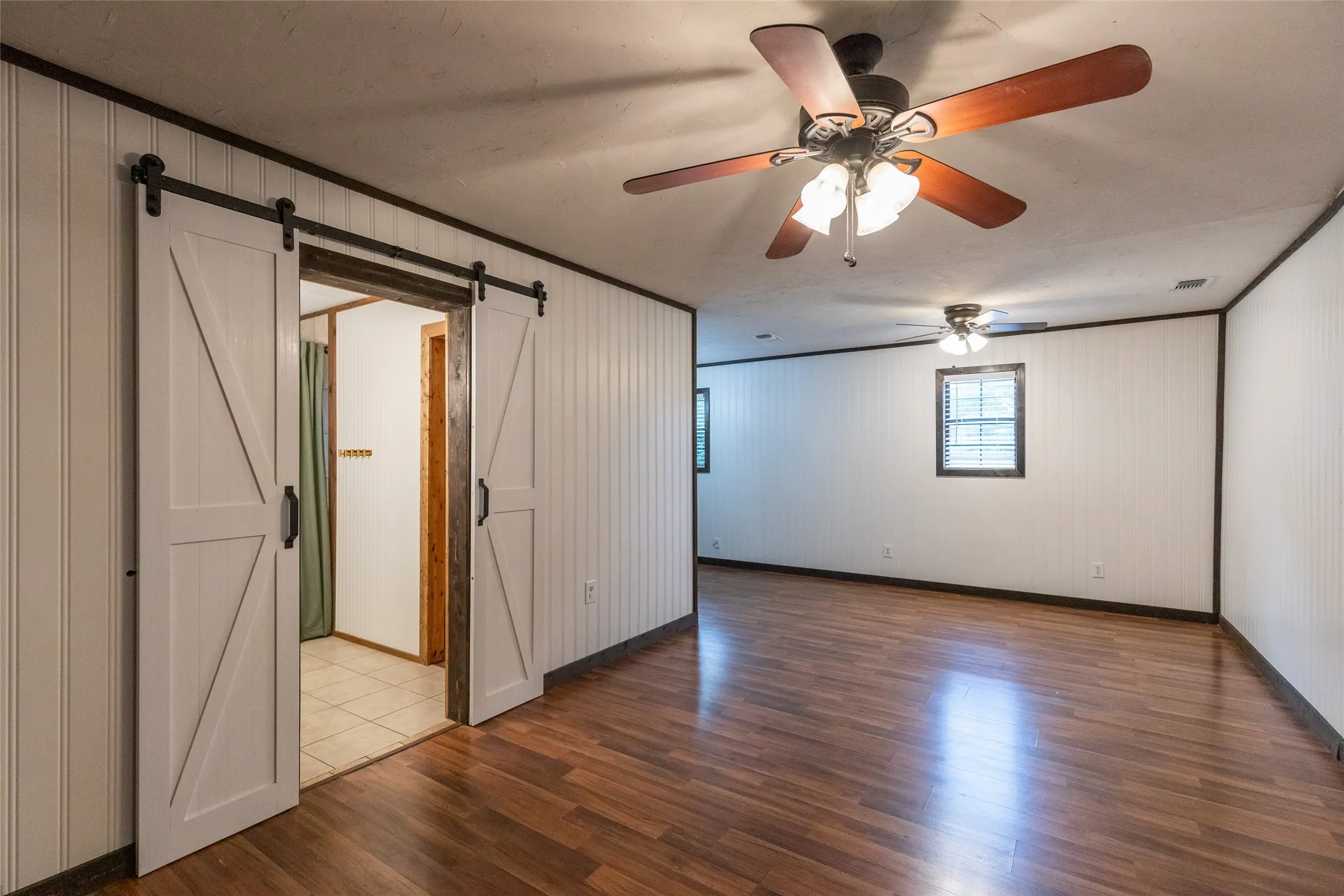 Spacious interior featuring wood-finish flooring and white beadboard paneling