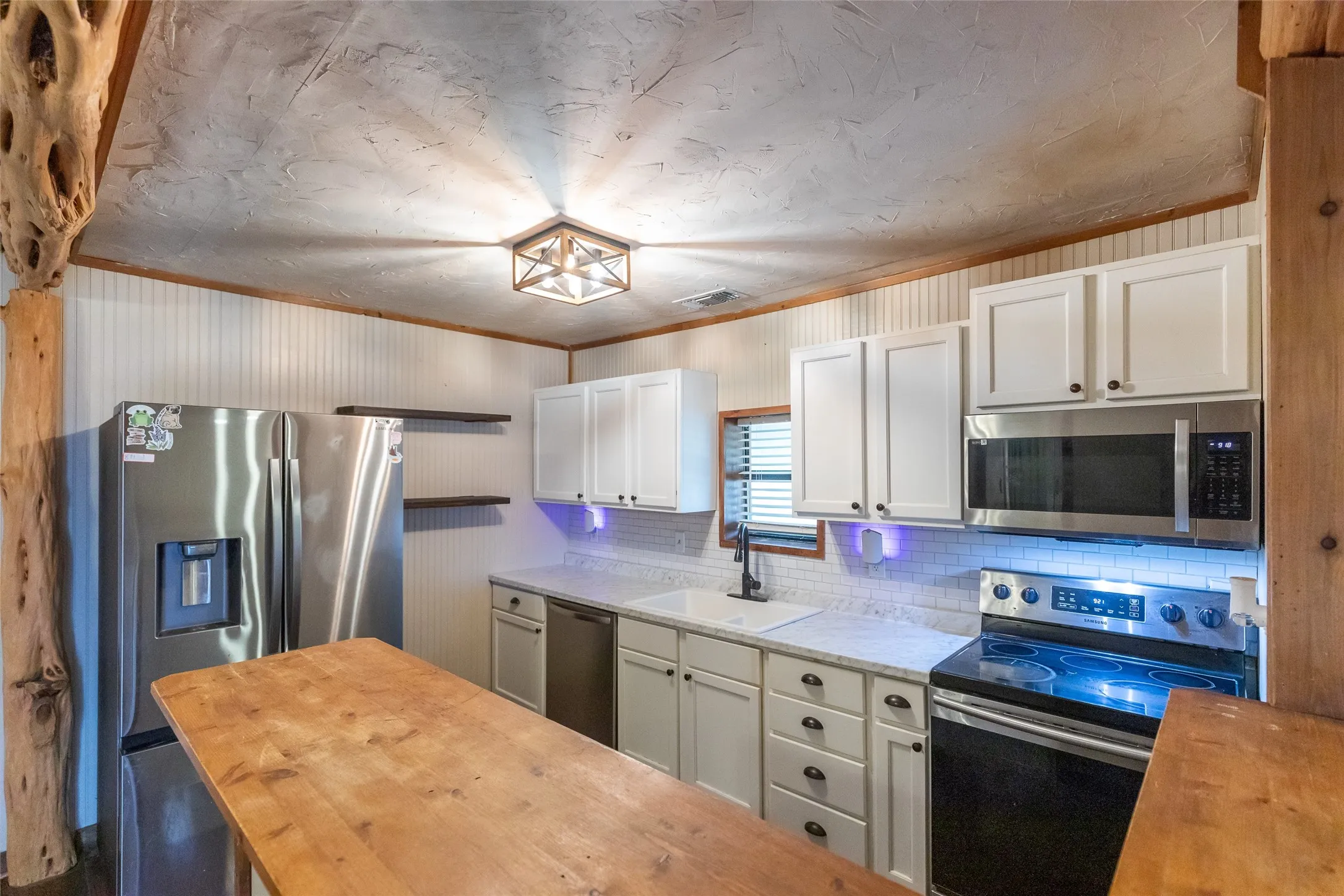 Kitchen featuring a wood-finish counter, white shaker-style cabinetry, stainless steel appliances, and a wood-beamed ceiling
