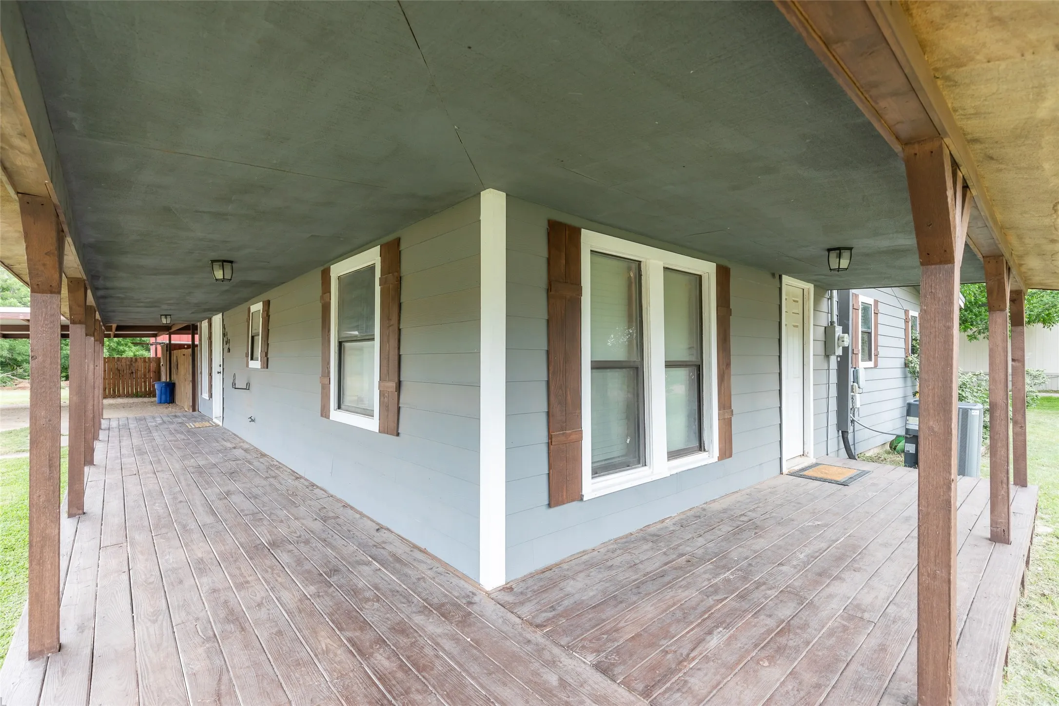 Wrap-around porch featuring wood-finish flooring, sturdy wood posts, and a dark ceiling