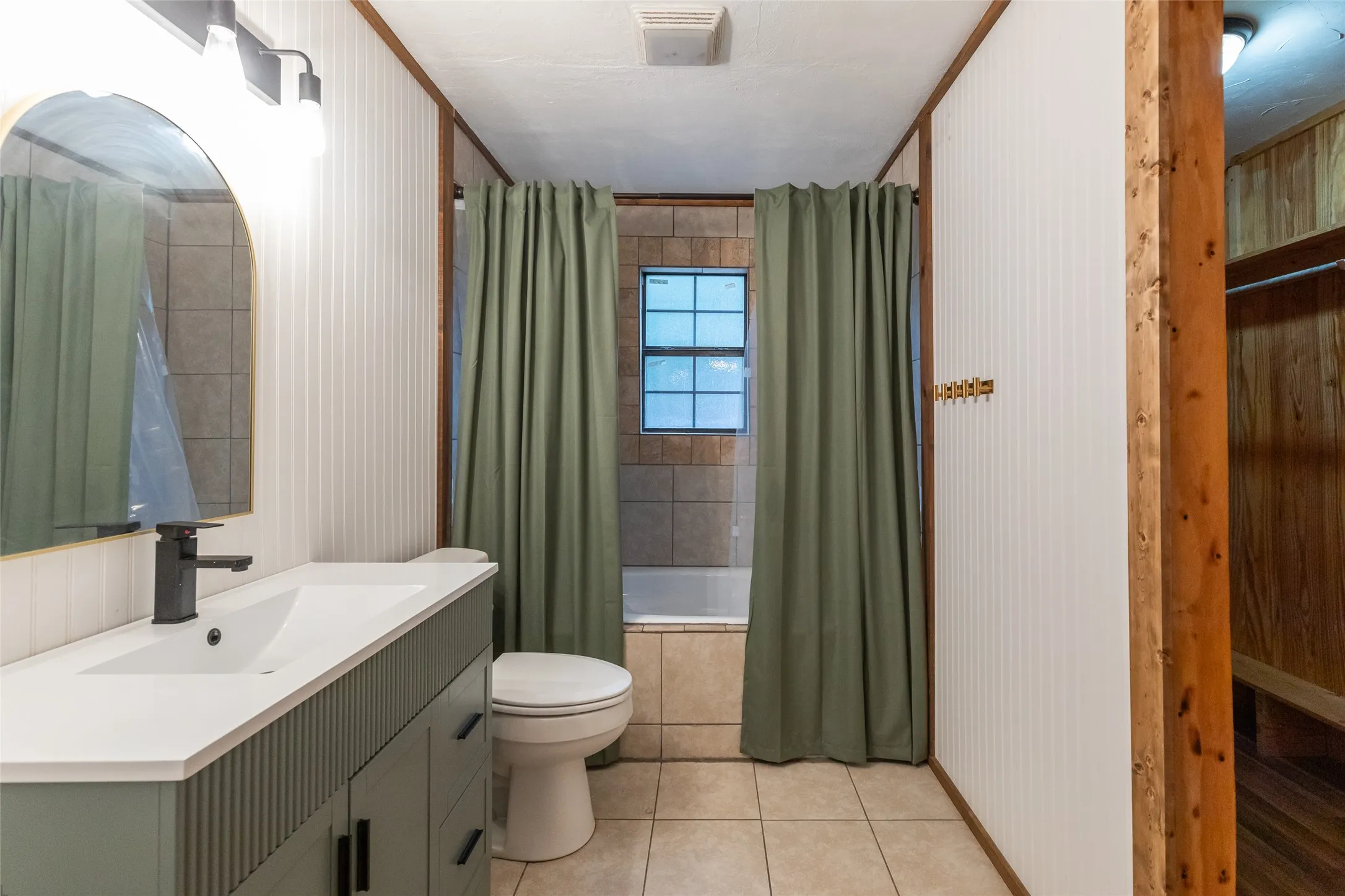 Bathroom featuring a vanity with an integrated sink, matte black faucet, and an arched mirror