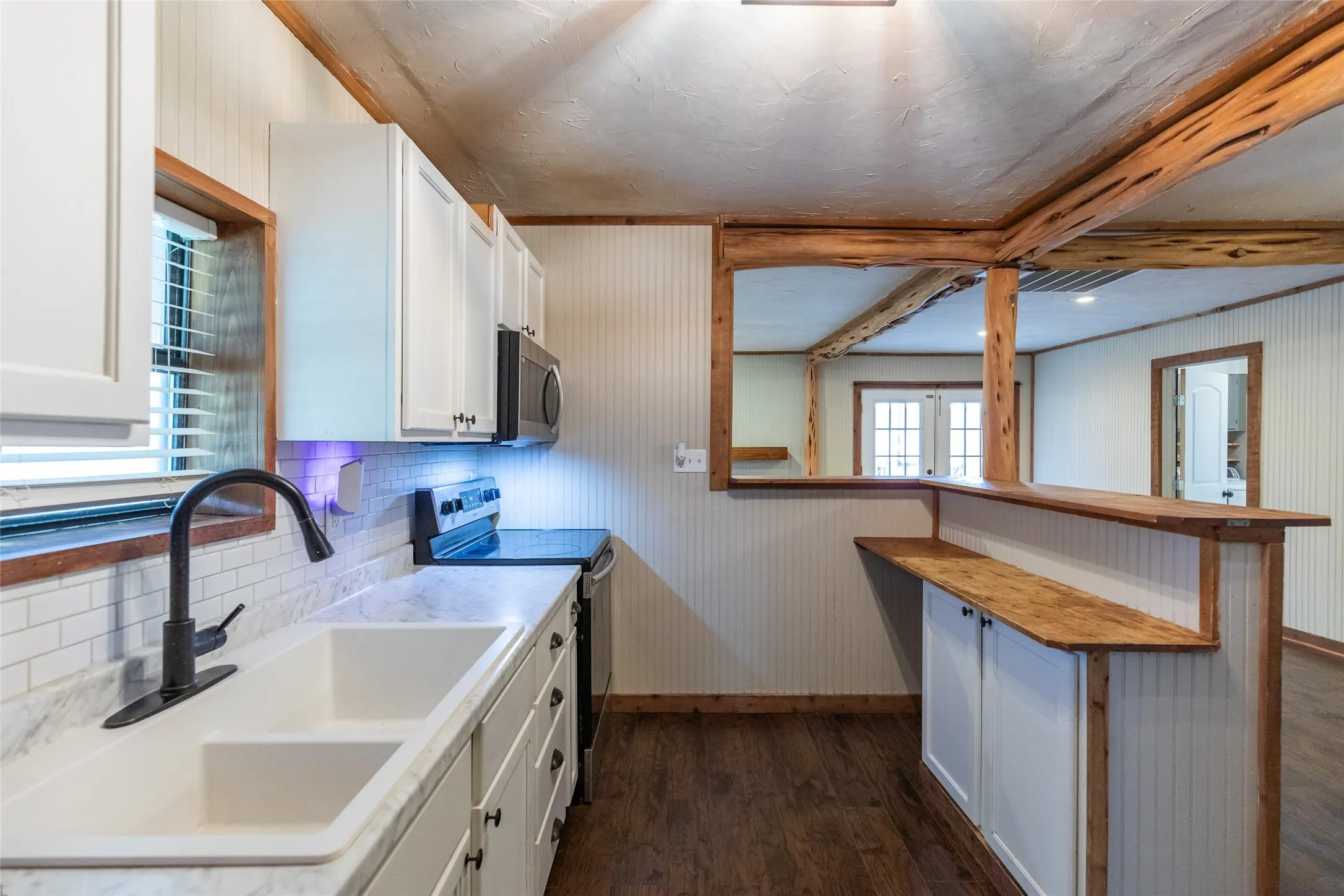 Kitchen featuring white cabinetry, a dual-basin sink with a matte black faucet, and a subway tile backsplash