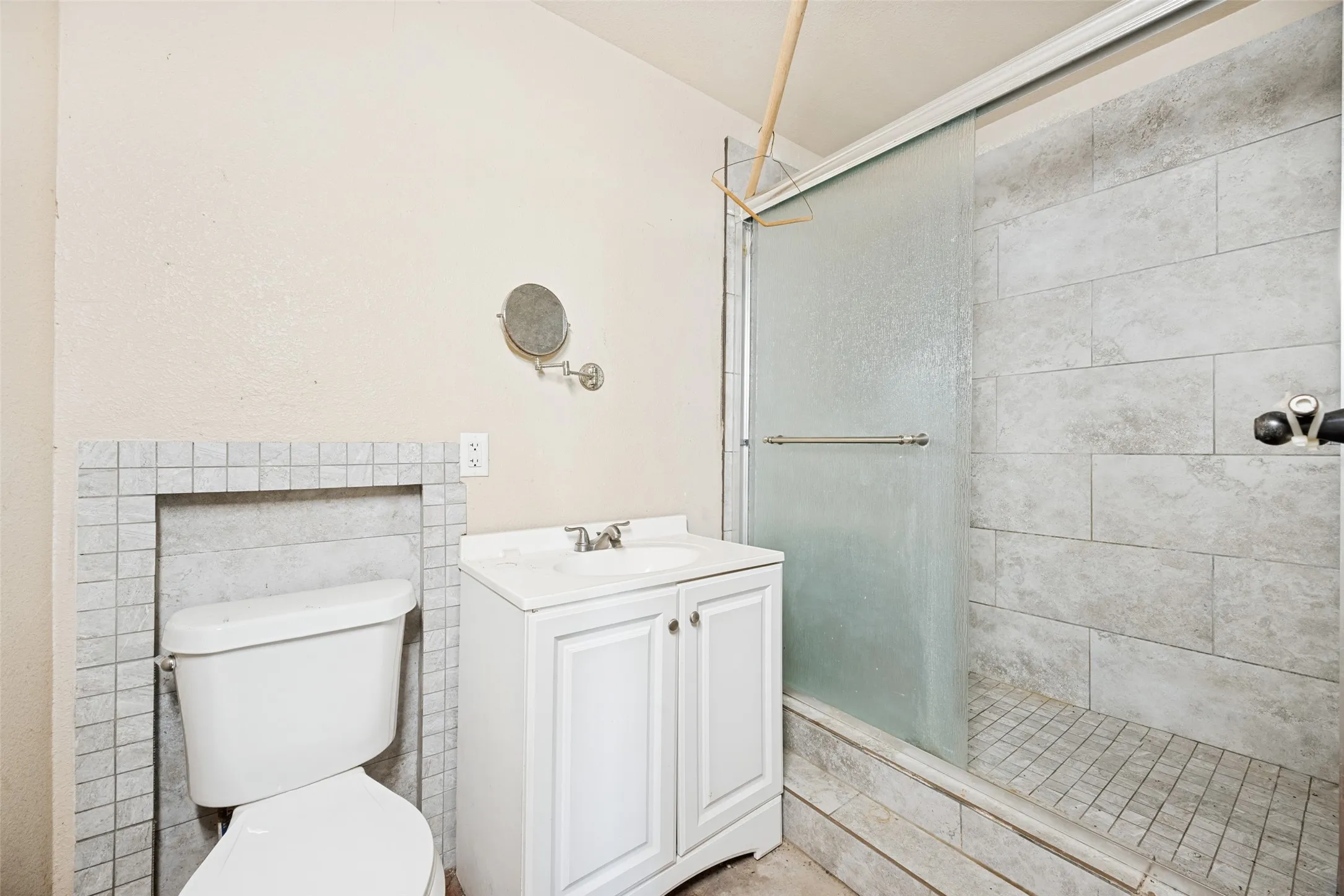 Full bathroom with a sliding glass shower door, a white vanity with an integrated sink, and a tiled shower surround