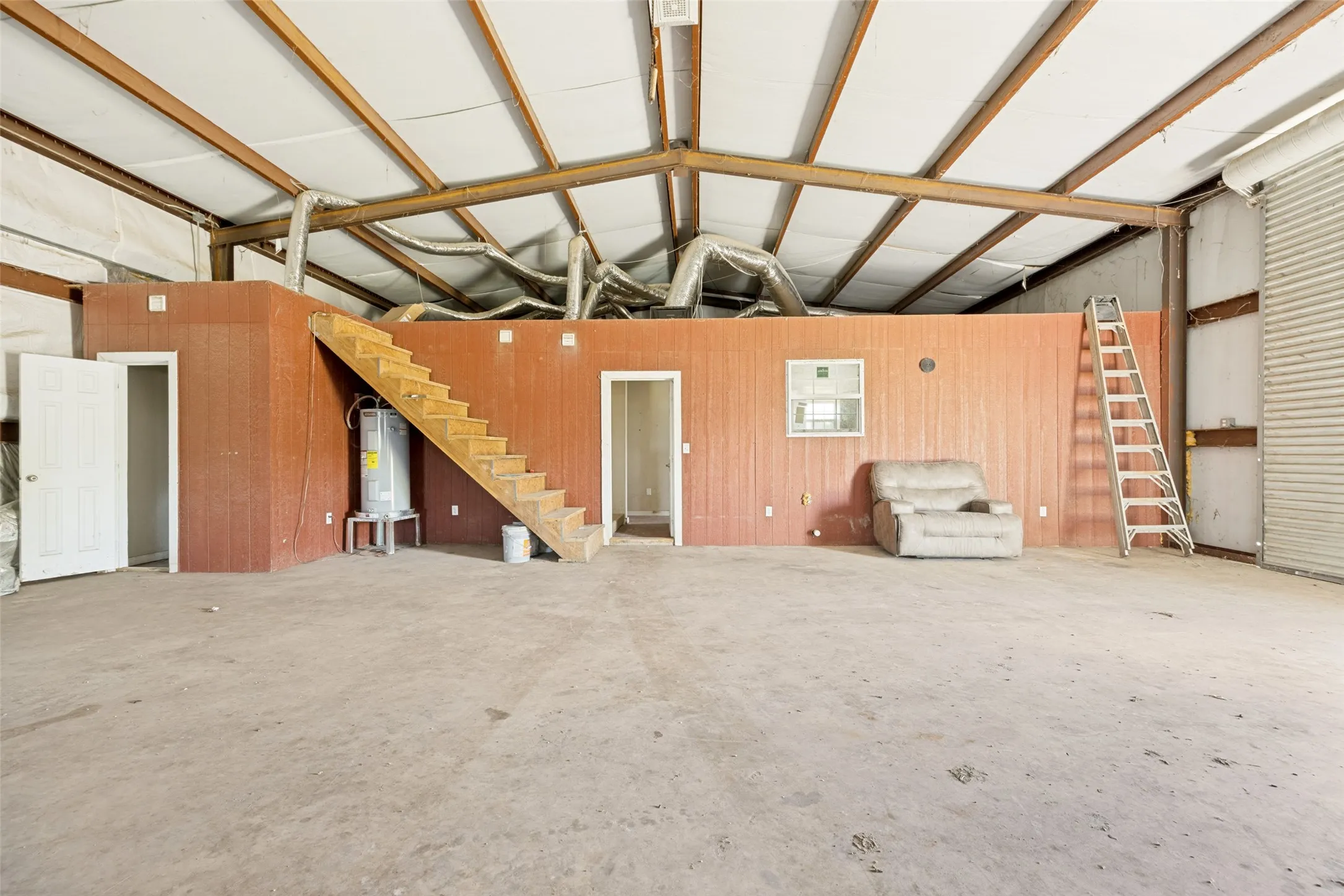 Spacious interior featuring a high ceiling with exposed structural beams and extensive ductwork