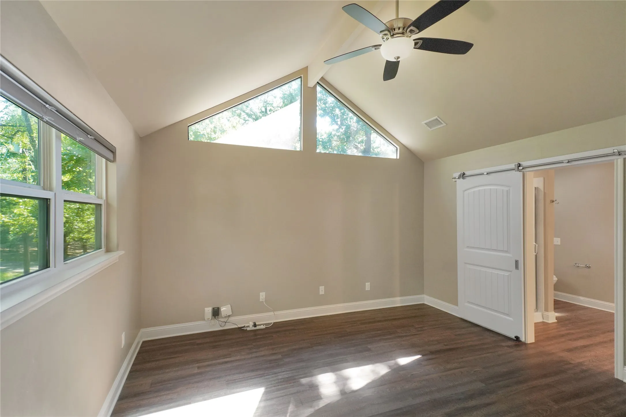 Room featuring vaulted ceilings, wood-finish flooring, and multiple window placements