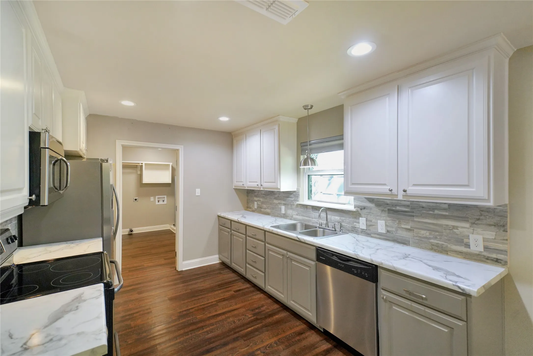 Kitchen featuring white upper cabinetry, gray lower cabinetry, and marbled countertops