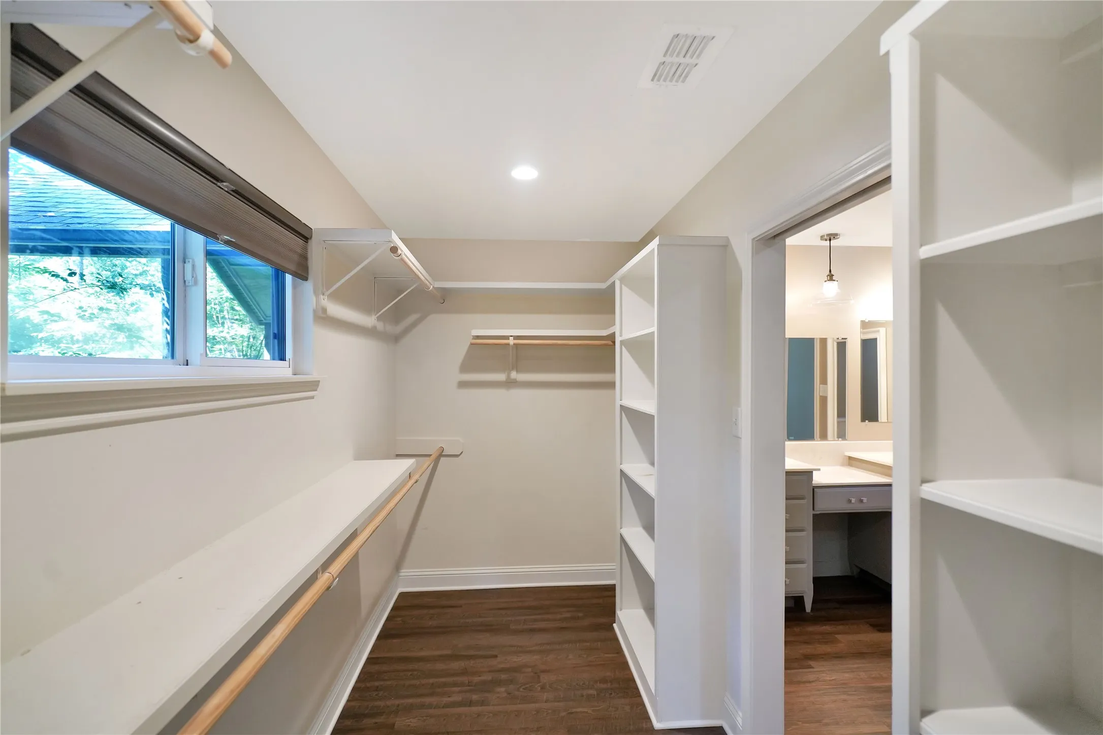 Spacious walk-in closet featuring wood-finish flooring, built-in shelving, hanging rods, and recessed lighting