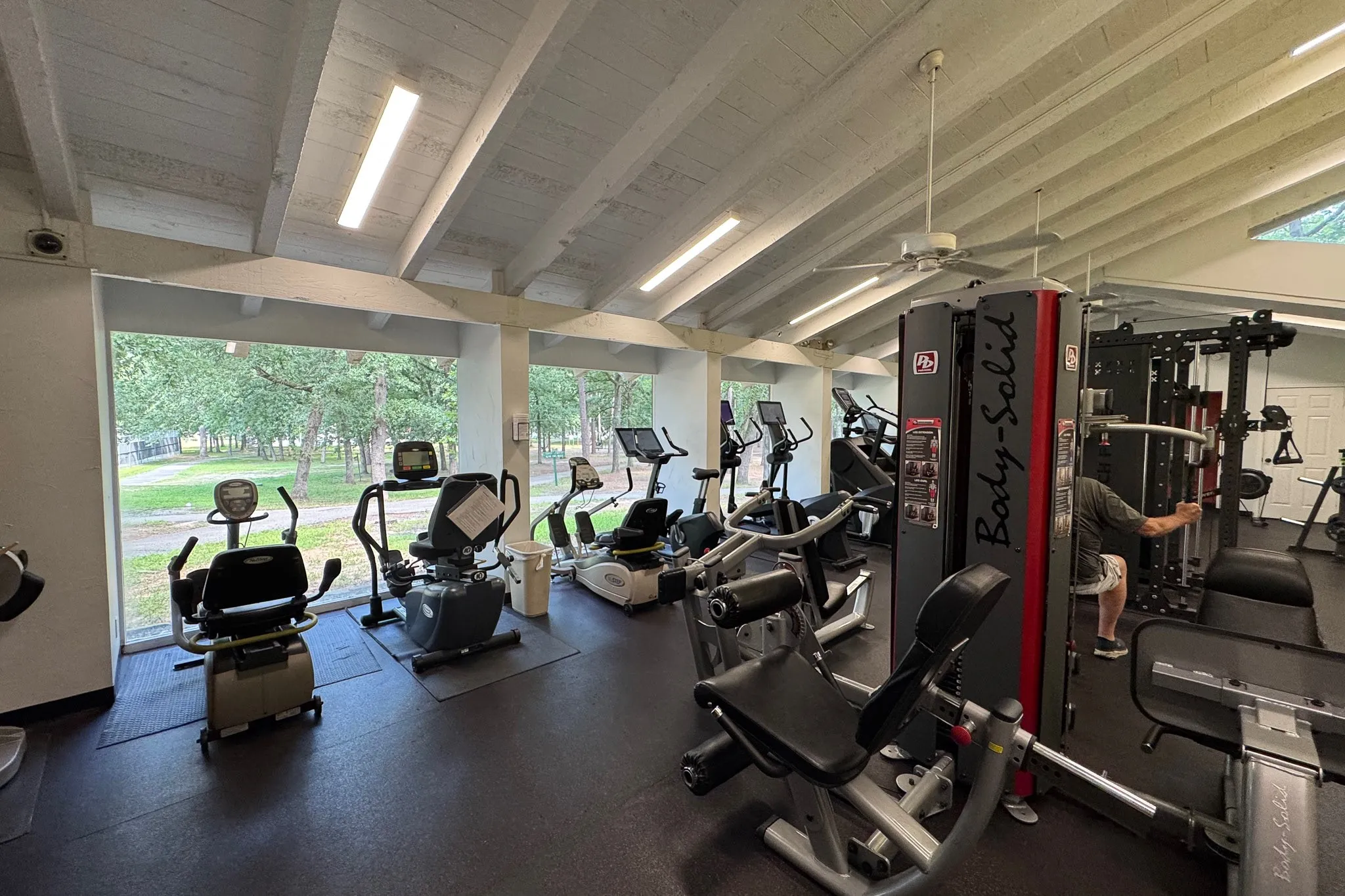 Fitness center with vaulted ceilings, exposed beams, and multiple cardio machines