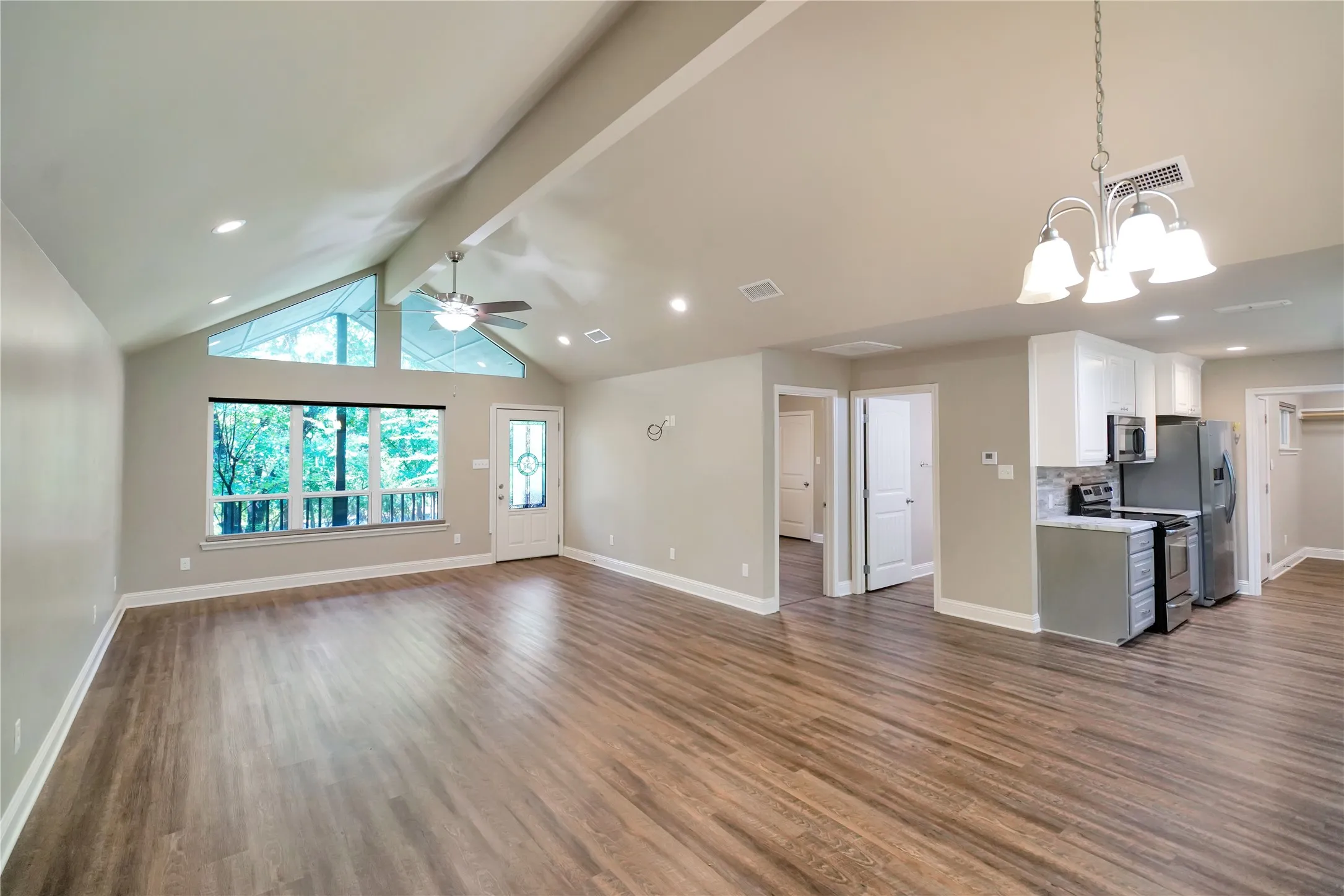 Spacious room featuring vaulted ceilings, wood-finish flooring, recessed lighting, and a contemporary ceiling fan