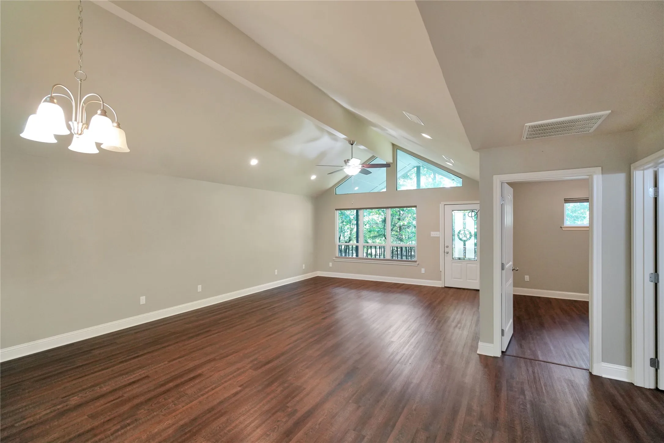 Spacious room featuring vaulted ceilings, wood-finish flooring, and multiple windows