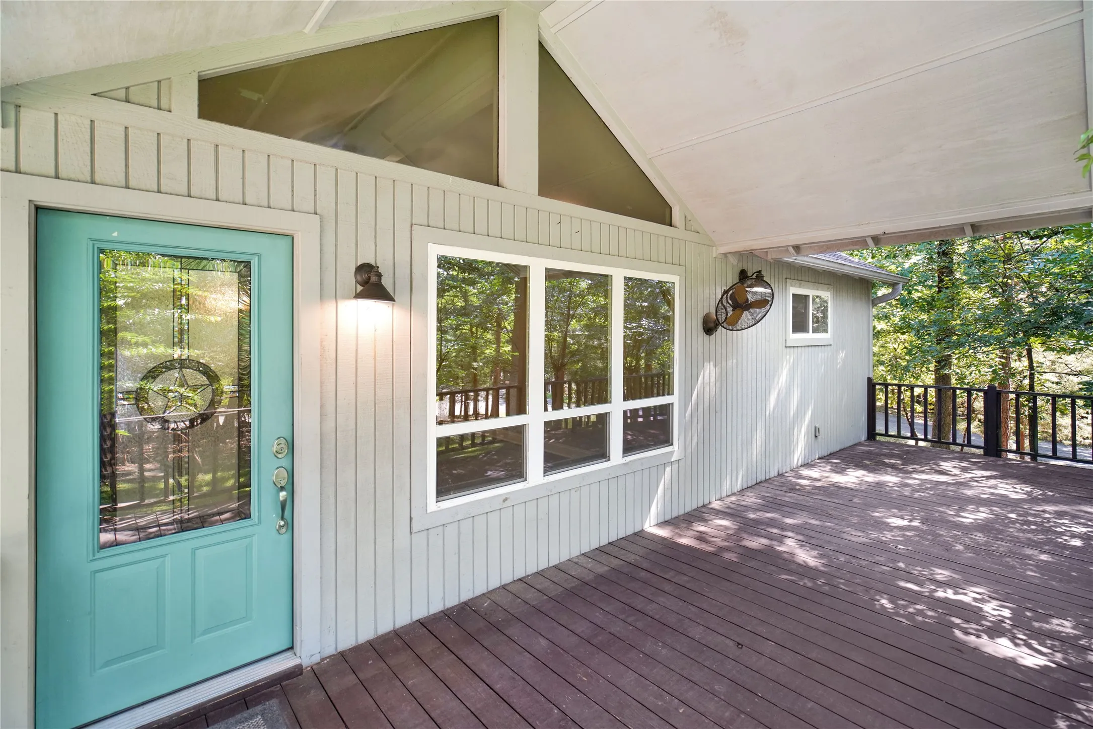 Expansive outdoor deck featuring composite wood-finish flooring, a covered patio, and a decorative wall-mounted fan