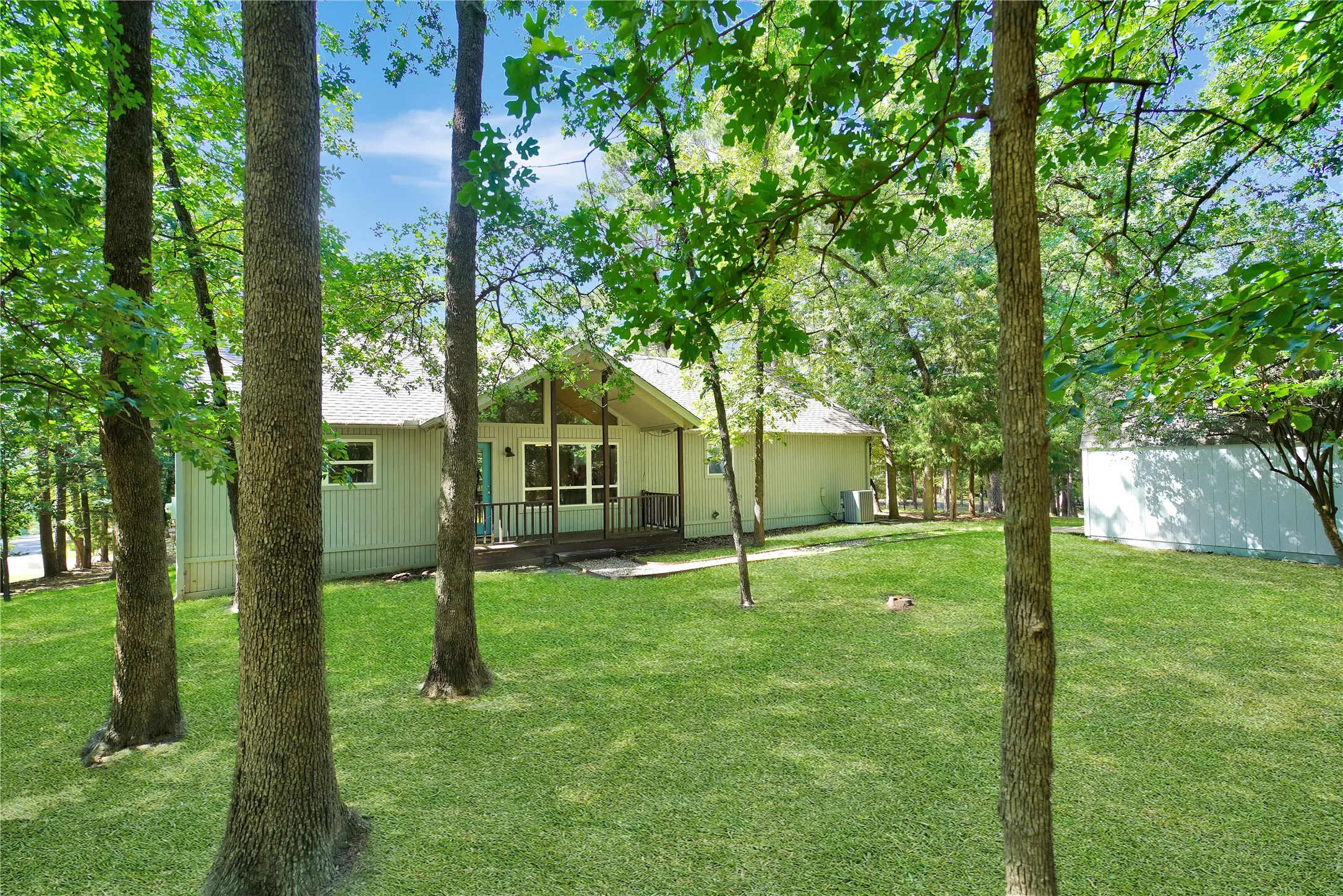Expansive green lawn with mature trees providing natural shade