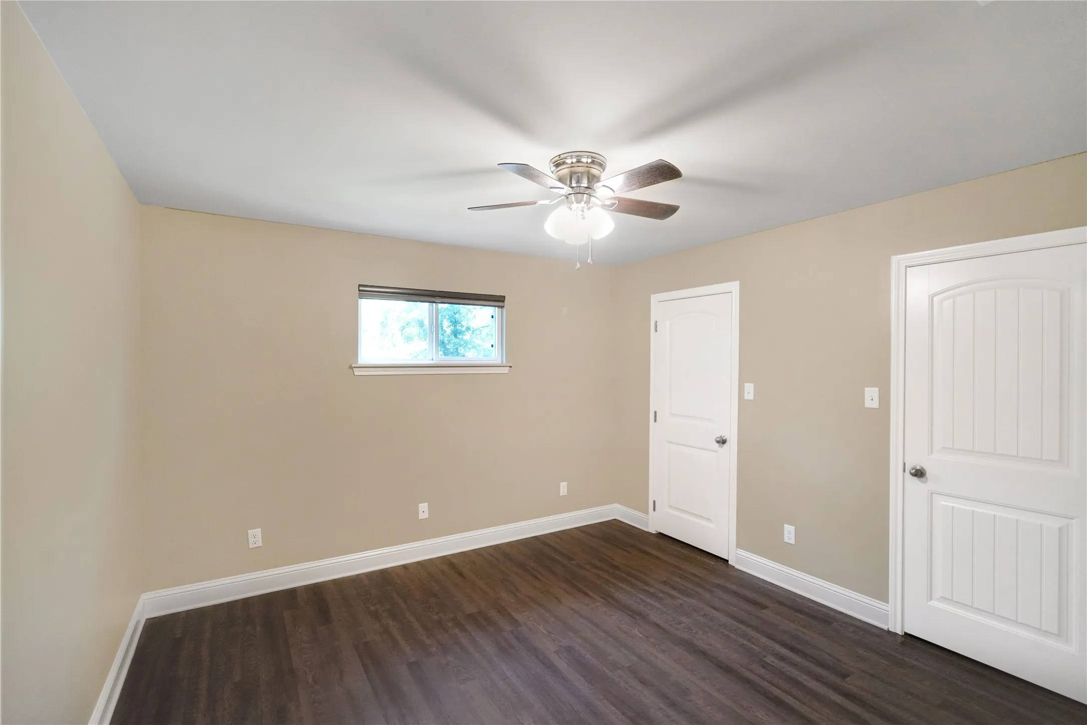 Room featuring wood-finish flooring, a ceiling fan with light, a window with blinds, and two paneled interior doors